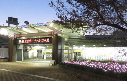 京王閣競輪場の正門。夕暮れにイルミネーションがはえる