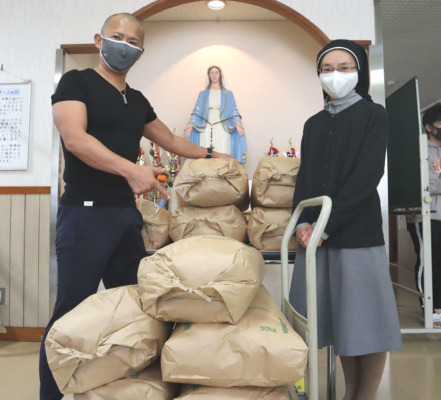 新米300キロを贈呈した中井大介（左）と「カリタスの園　天使育児園」職員の北川亜佐美さん