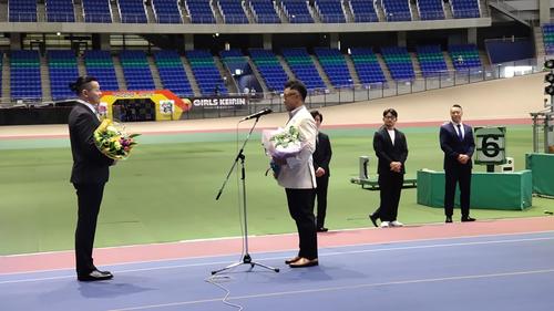 斎藤登志信（右）がサプライズで登場すると場内のファンから歓声が上がる。稲村成浩さんに花束を贈る（撮影・24年8月18日）