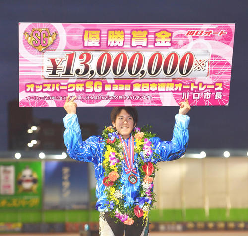 大会4連覇を達成した鈴木圭一郎は賞金ボードを掲げる（撮影・柴田隆二）