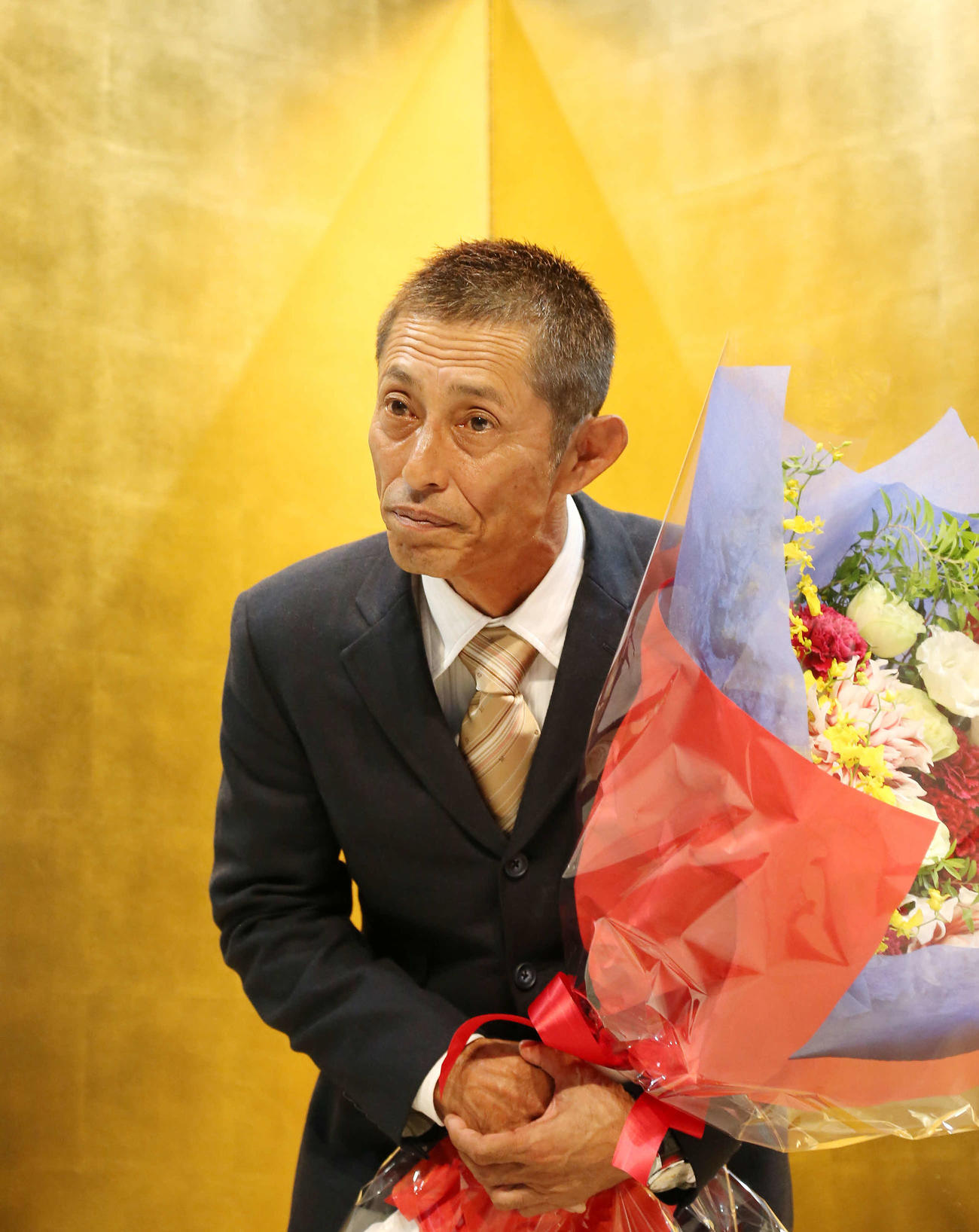 花束を手に一礼して引き揚げる今村豊さん（撮影・丹羽敏通）