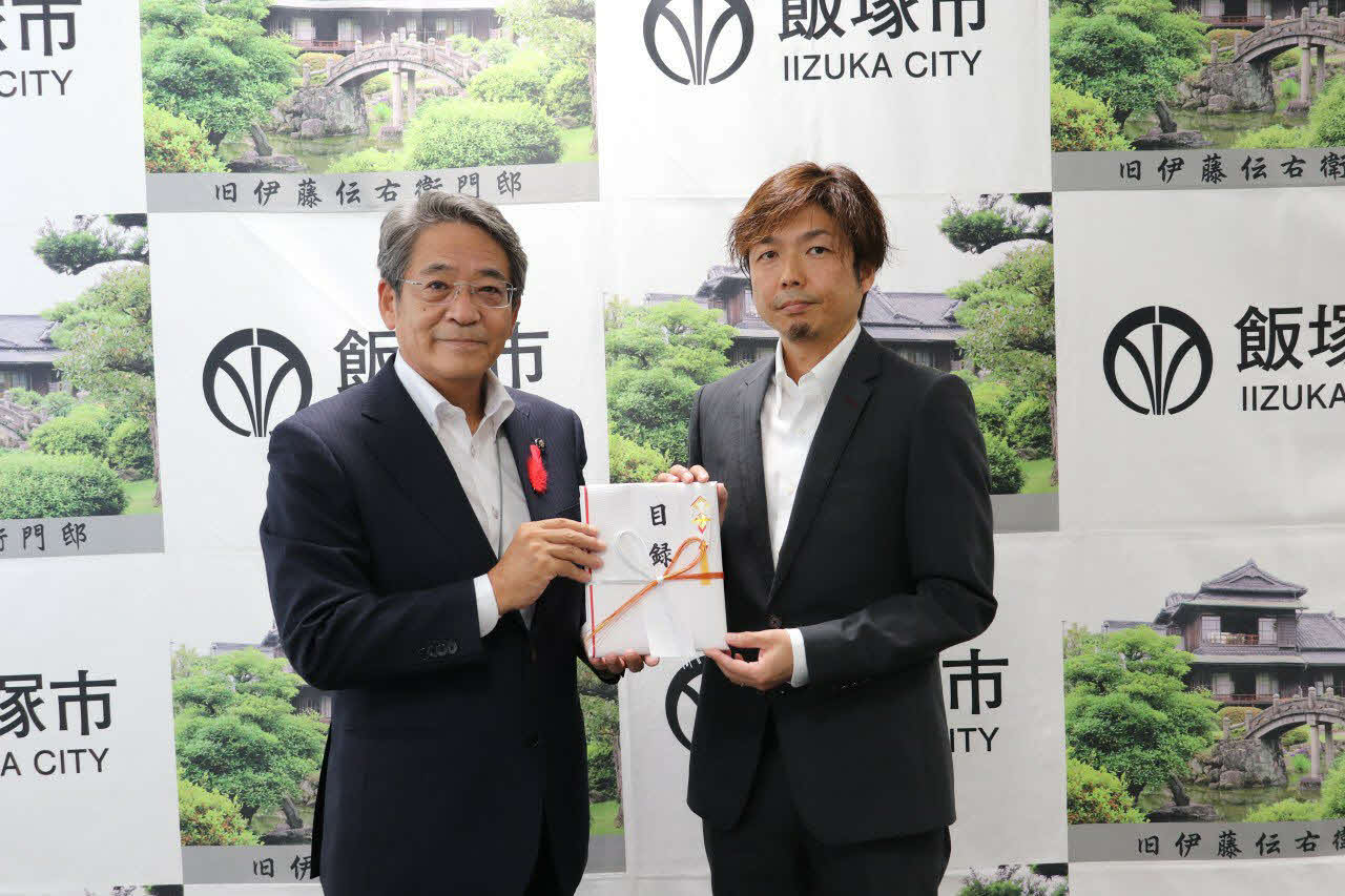 令和2年7月豪雨災害の義援金を渡す有吉辰也（右）と受け取る片峯誠市長（左）（飯塚市提供）