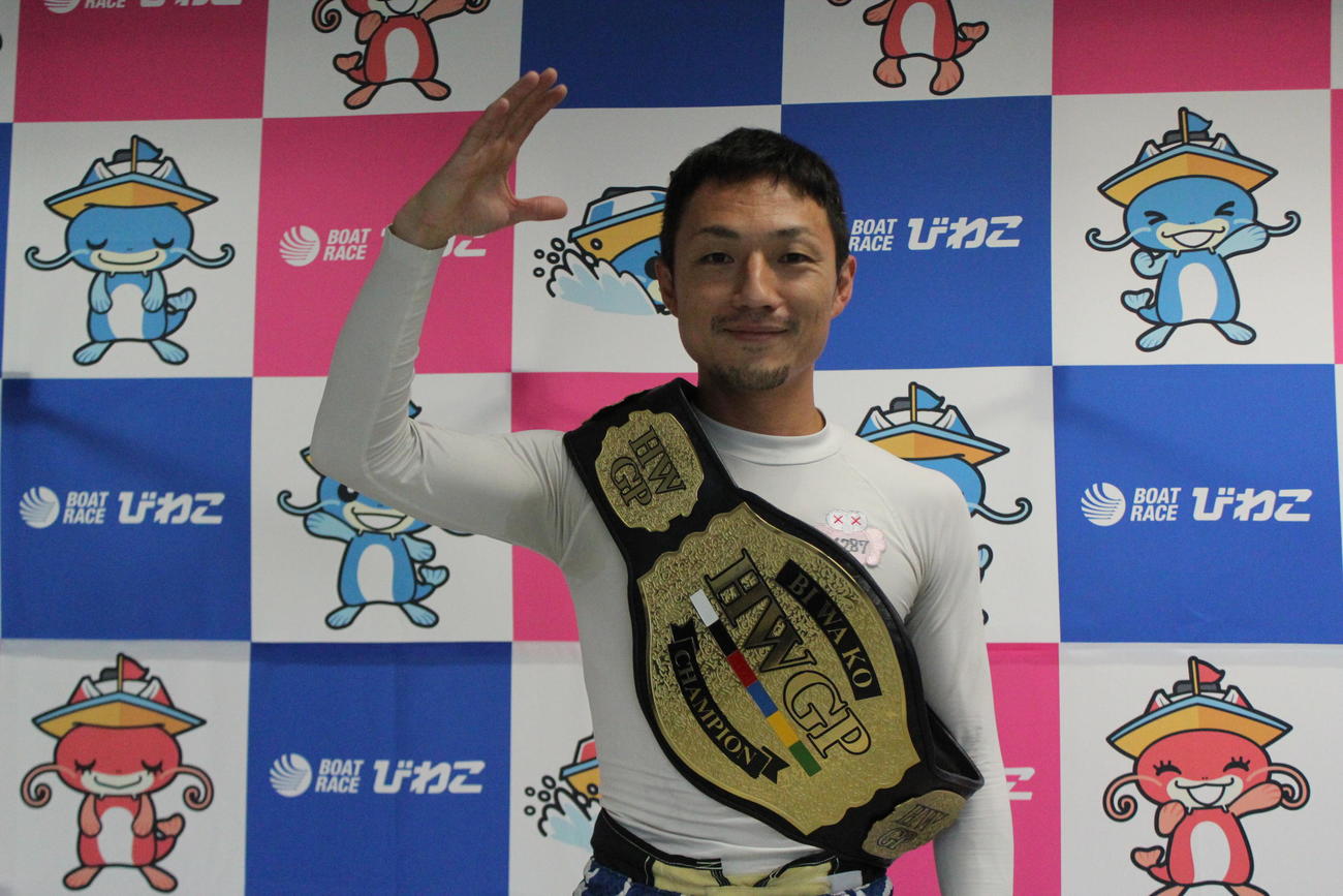 ヘビー級王の座に就いた今井貴士が、ベルトを肩に掛けて敬礼ポーズ
