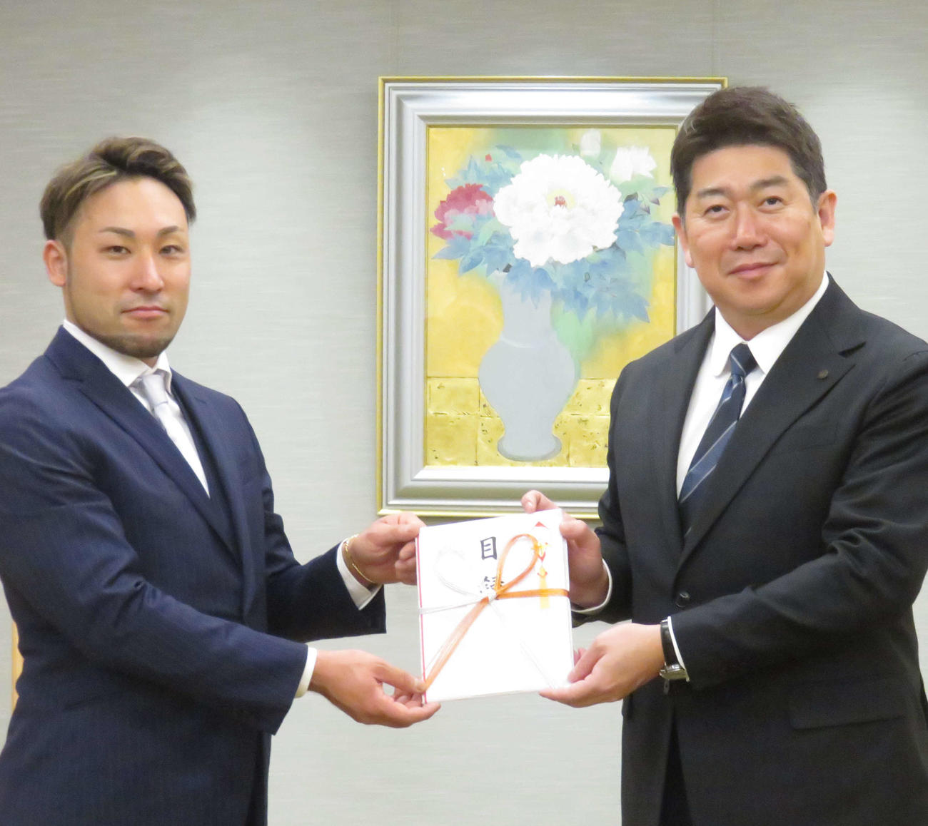 郡司浩平（左）が福田紀彦川崎市長に寄付の目録を手渡す