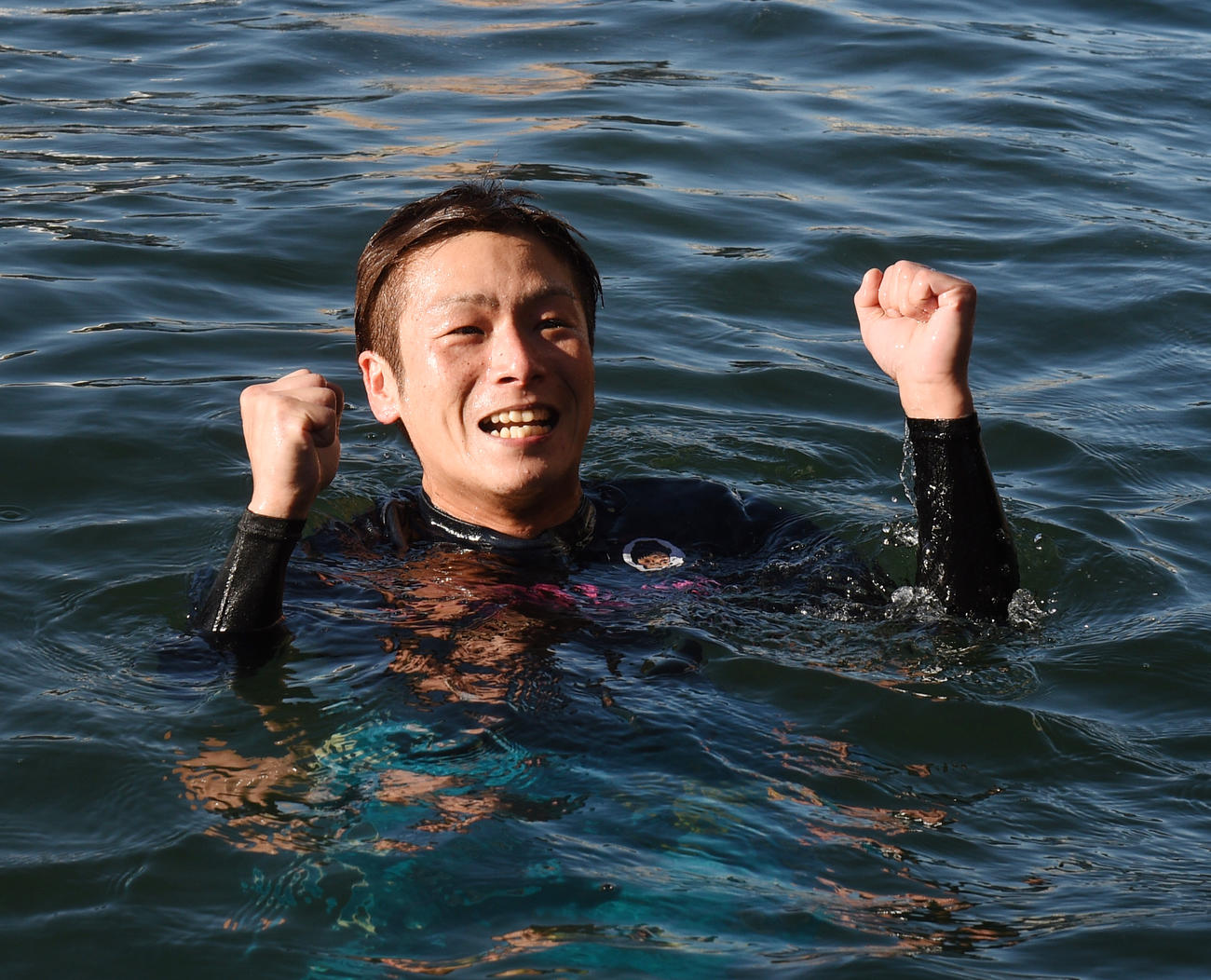 水神祭で水面に投げ込まれガッツポーズする秦英悟（撮影・柴田隆二）