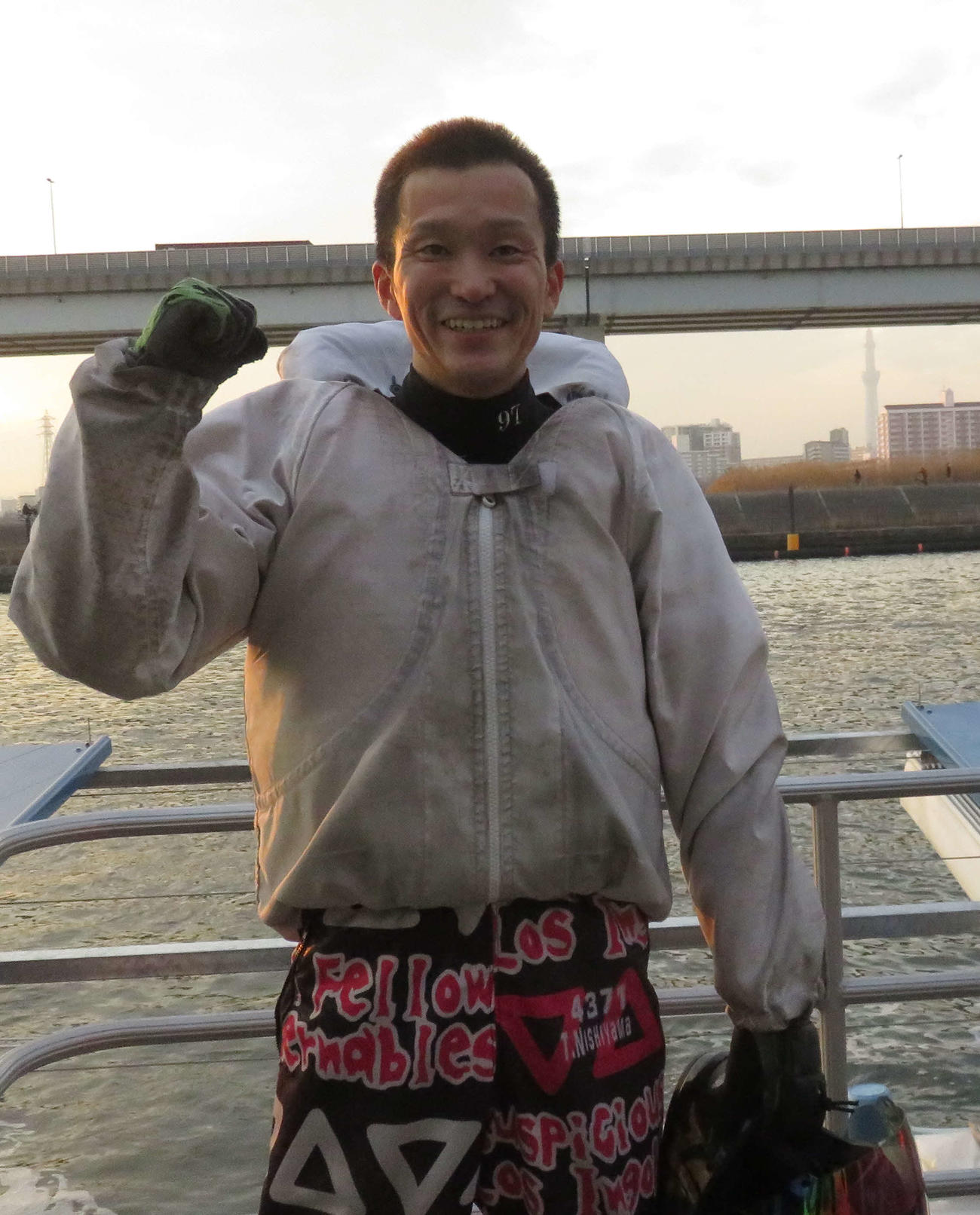 水面をバックにガッツポーズする西山貴浩