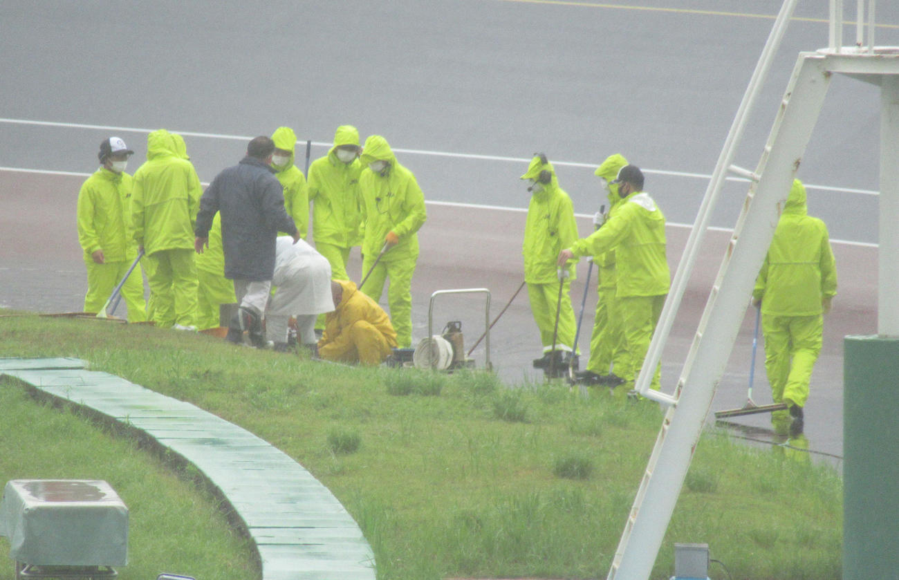 強い雨の中、係員が3コーナー付近で排水作業を行う