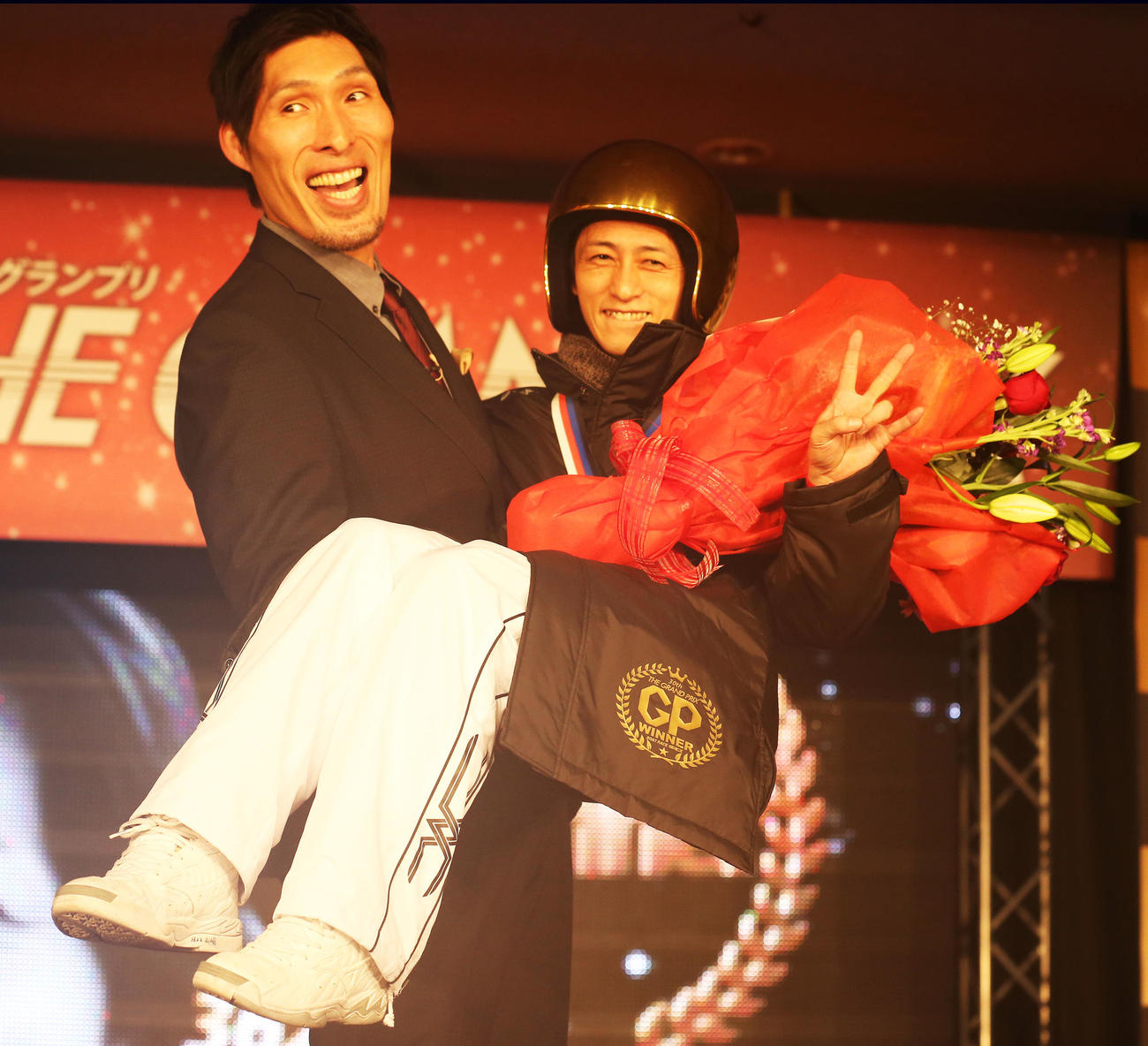 15年12月、グランプリの表彰式の後にプレゼンターの篠原信一氏から抱きかかえられピースサインをする山崎智也