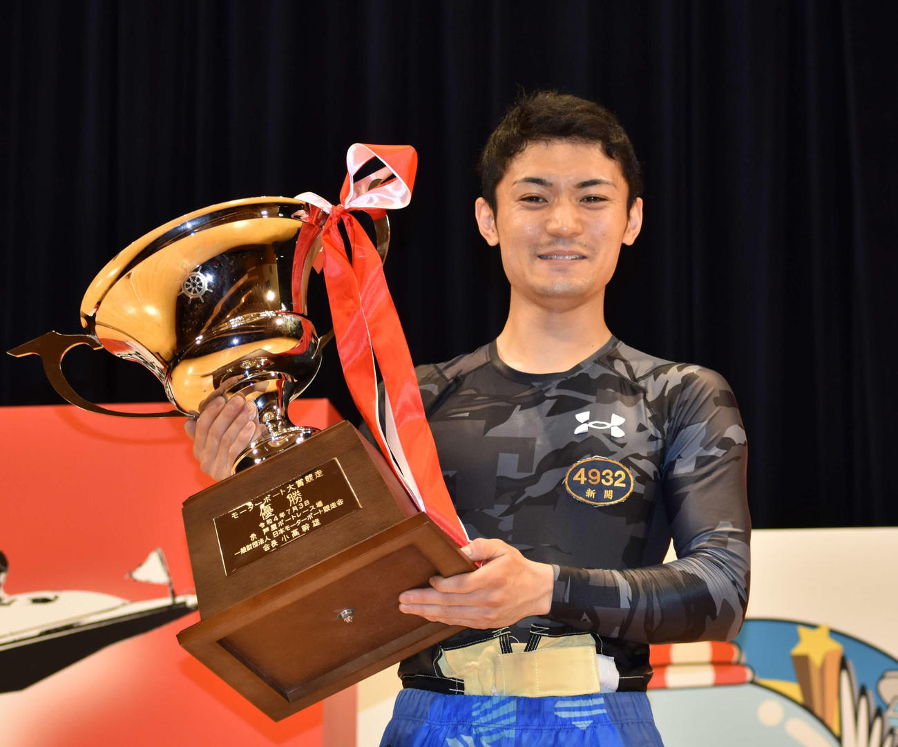 優勝した新開航は表彰式でトロフィーを手に笑みを浮かべる