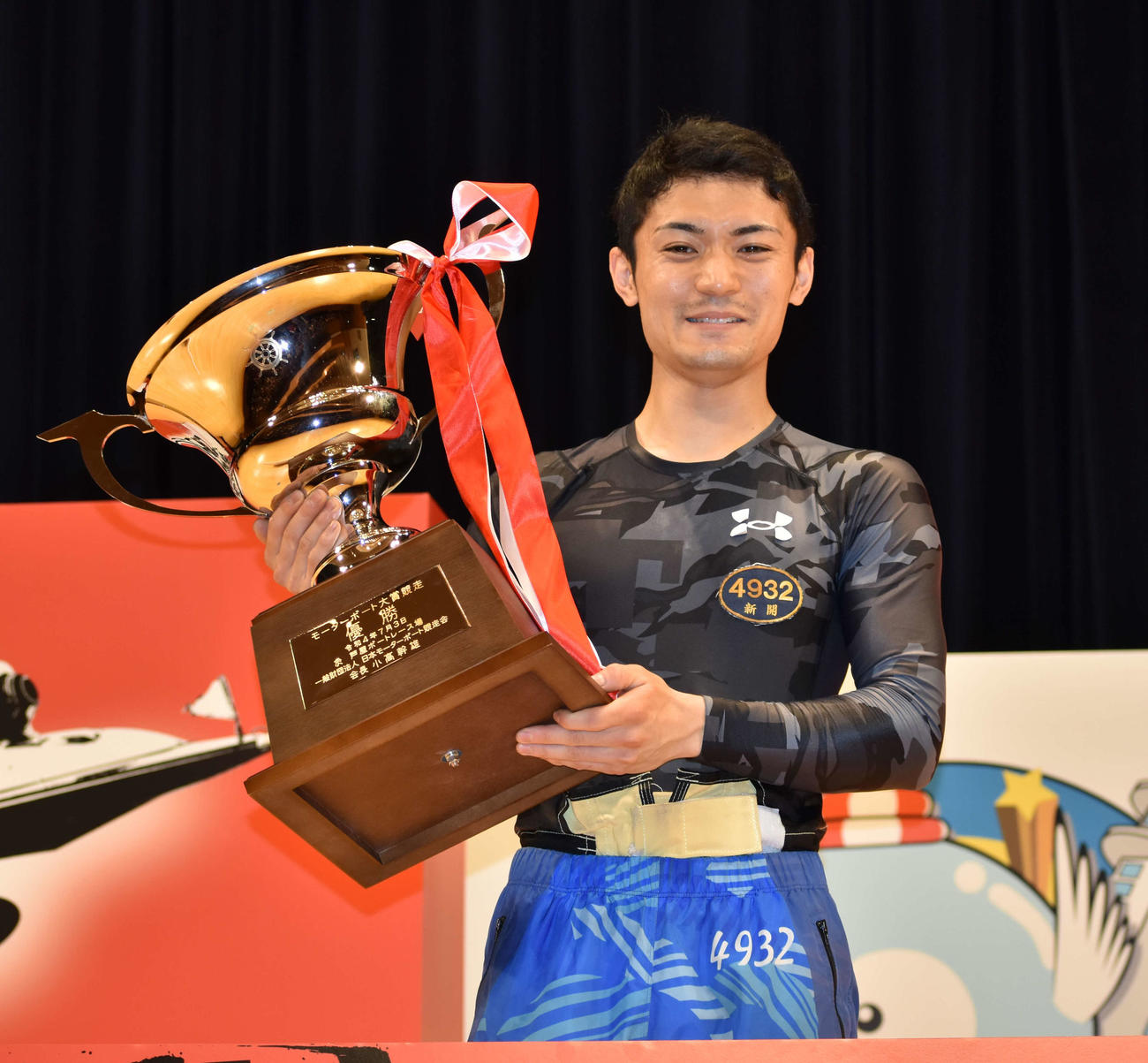 優勝した新開航は表彰式でトロフィーを手に笑みを浮かべる