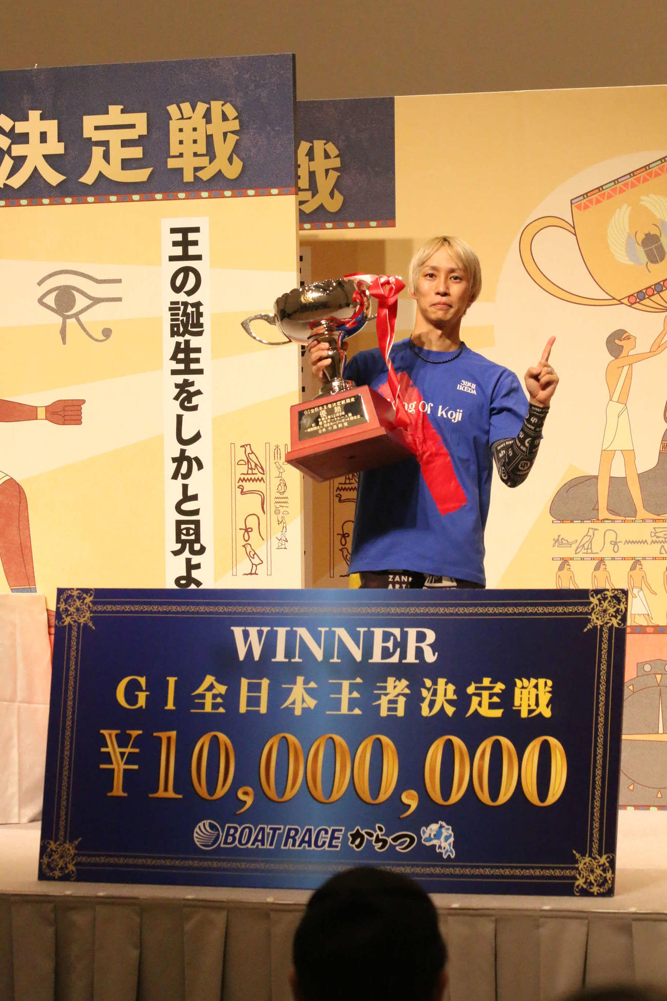 優勝した山田康二は賞金ボードを前にトロフィーを持ち、「1番」ポーズを見せた