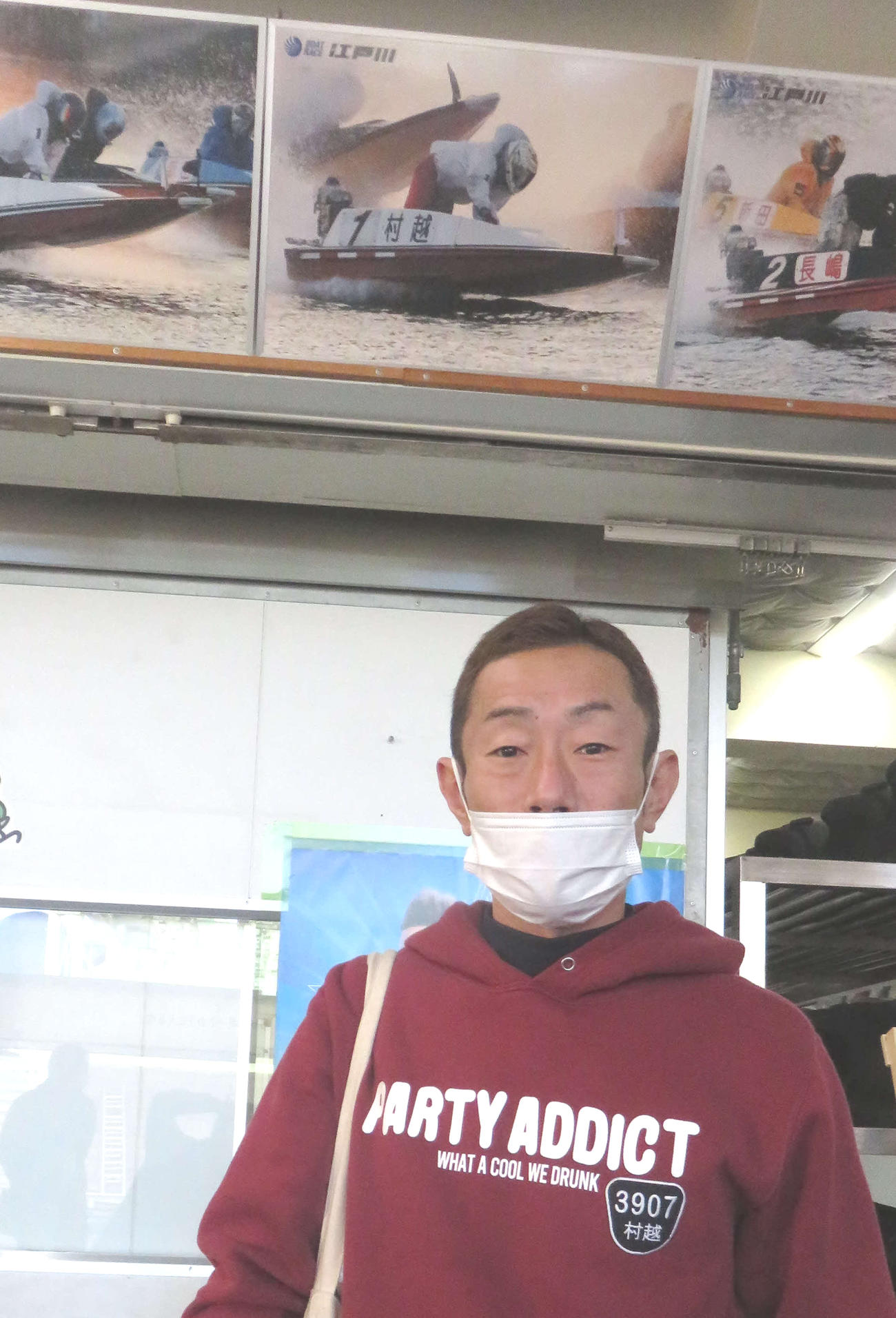 当地61周年記念ボードを背にする村越篤