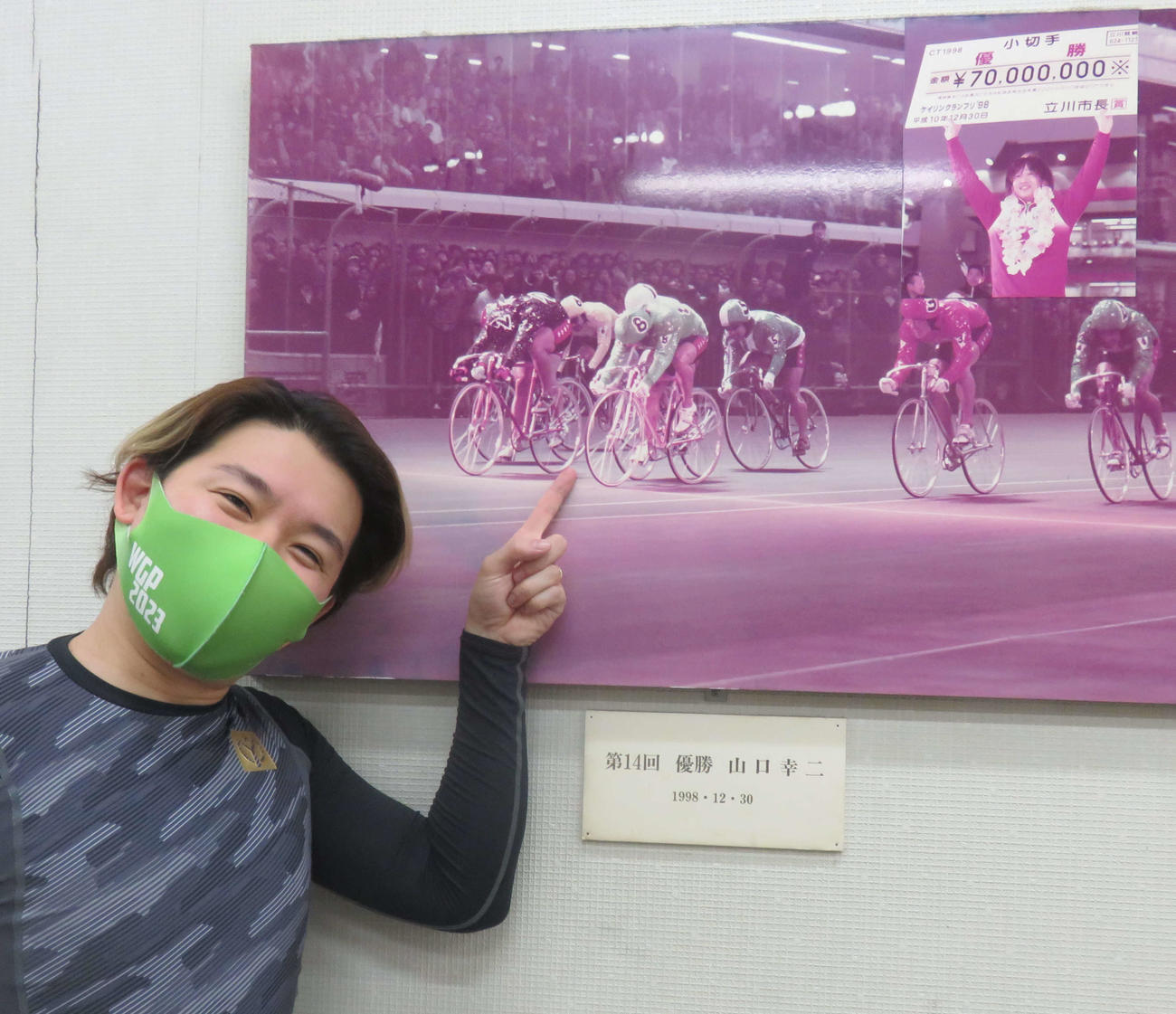 父幸二氏が勝った98年立川グランプリのパネルを指し示す山口聖矢（撮影・栗田文人）