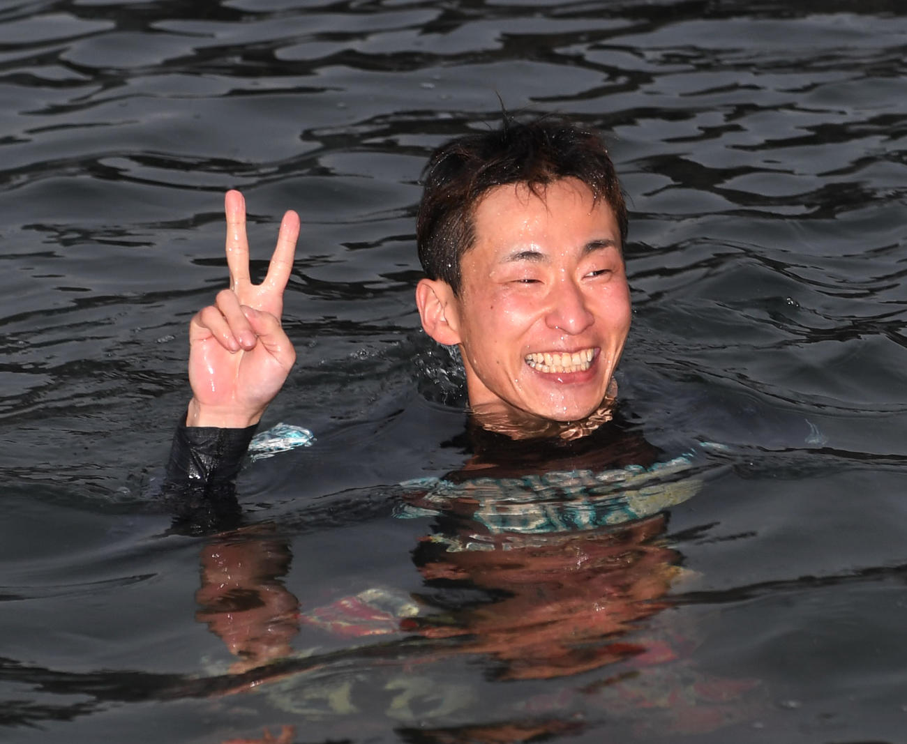 優勝した土屋智則は水神祭で水面に投げ込まれVサインする（撮影・柴田隆二）