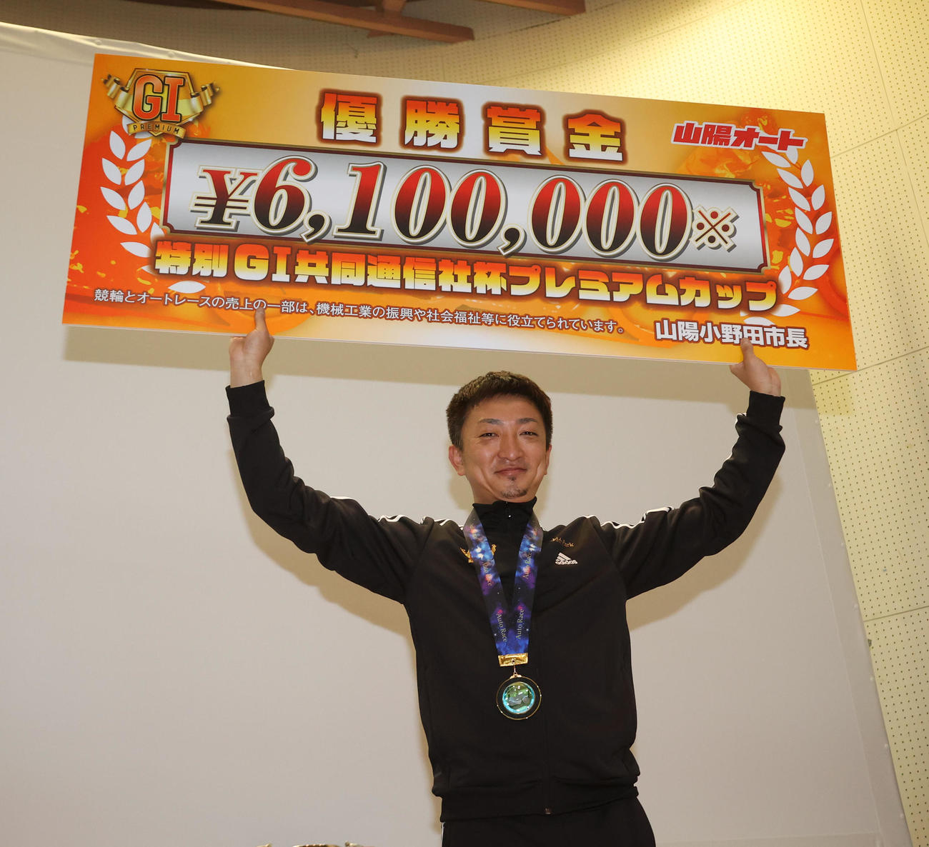 優勝した荒尾聡は賞金ボードを手に笑顔（撮影・梅根麻紀）