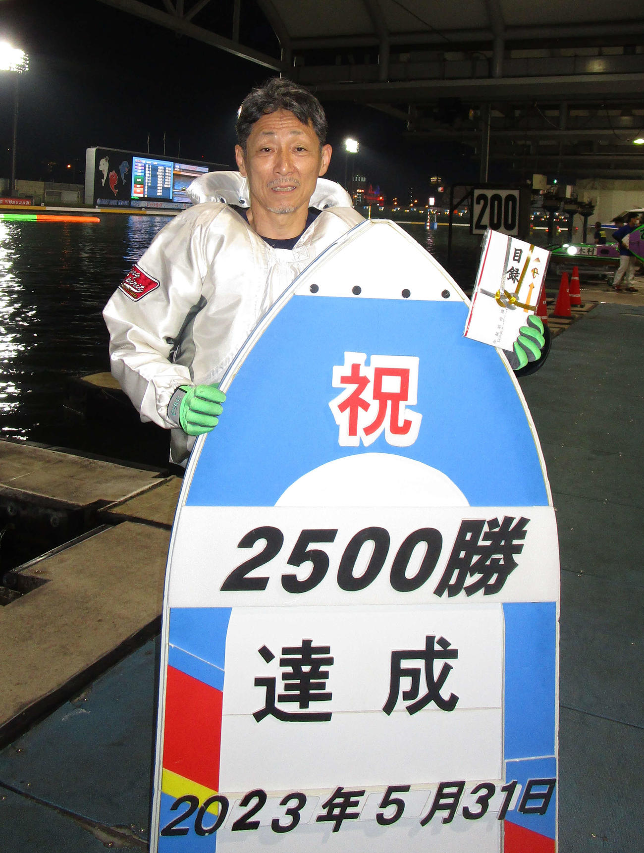 通算2500勝を達成し、記念ボードを前に笑顔を見せる江口晃生