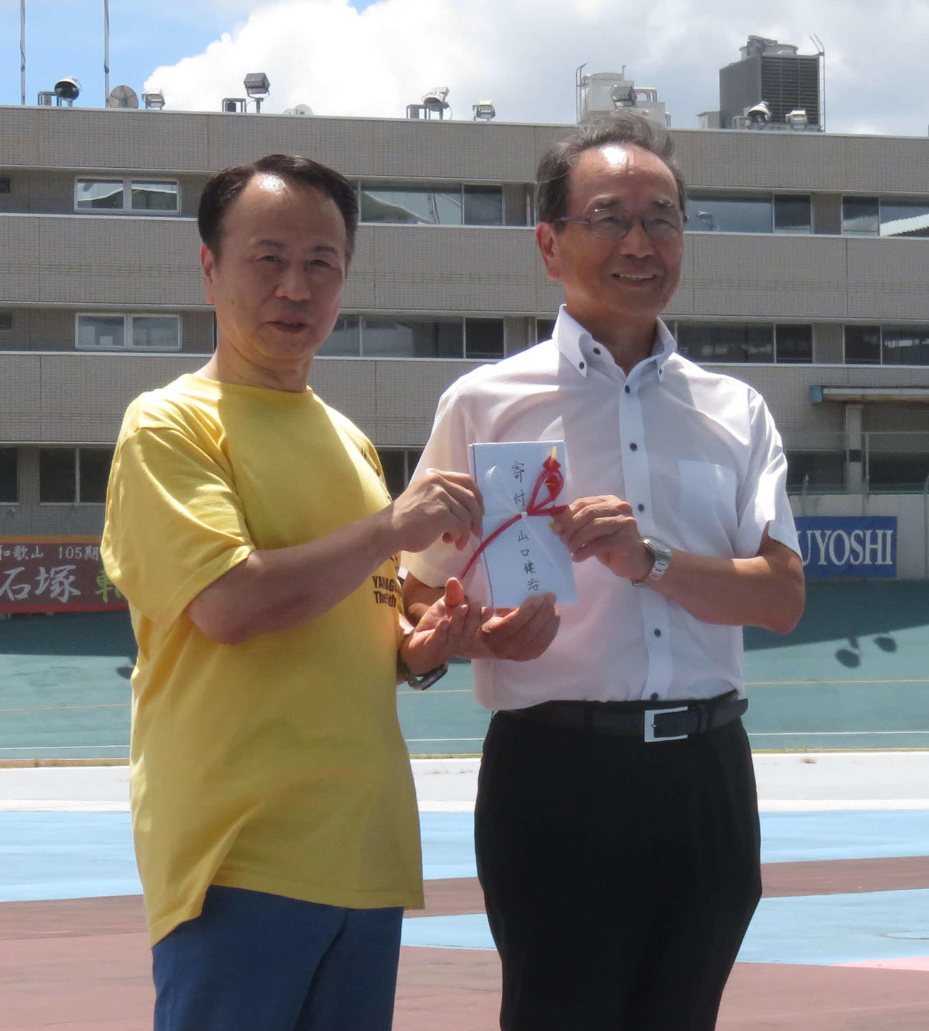 山口健治氏（左）が鈴木茂会長に寄付の目録を手渡す（撮影・野島成浩）