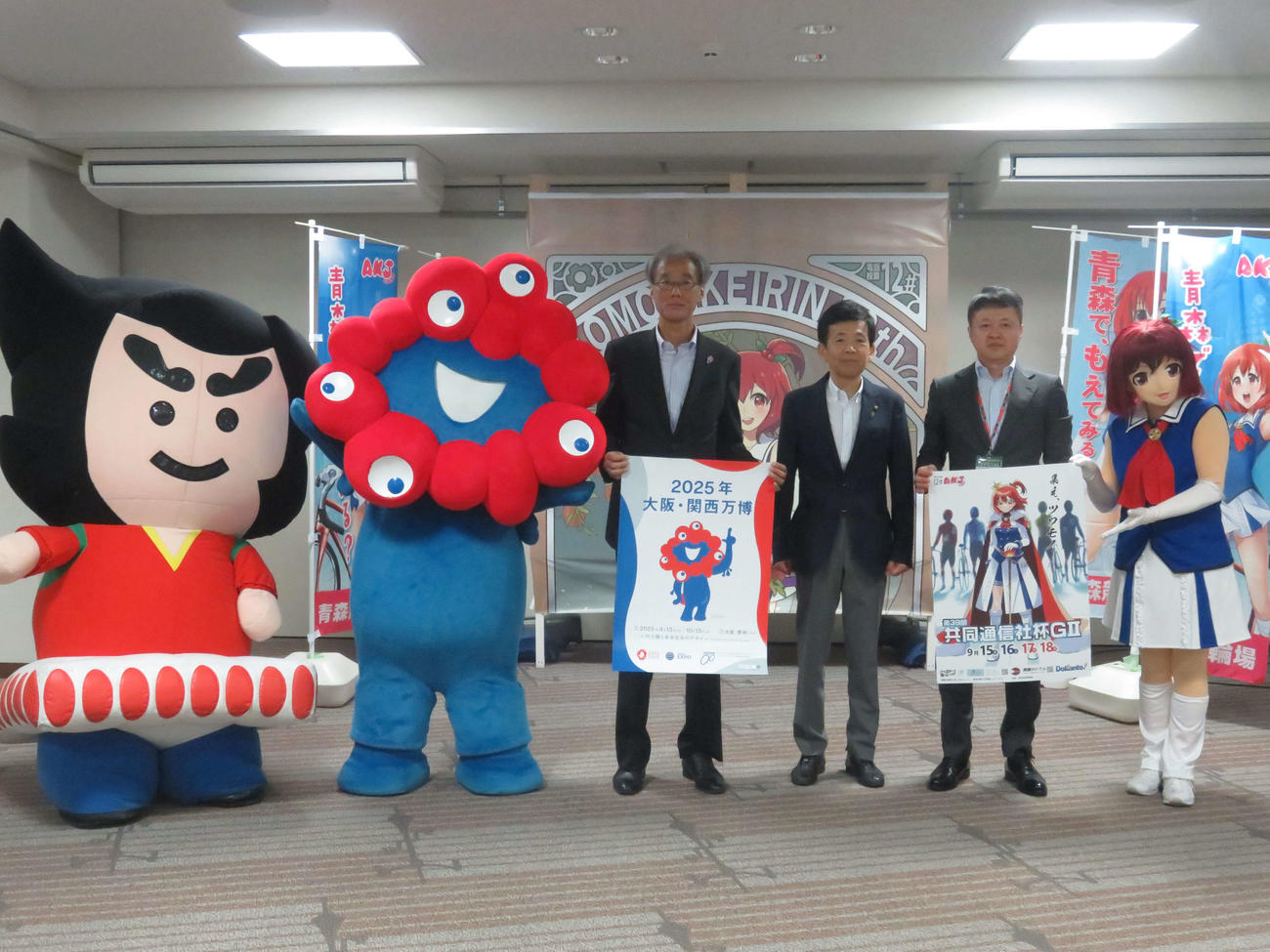大阪万博PRのため競輪場を表敬訪問したマスコット「ミャクミャク」（左から2人目）と、高科淳副事務総長（同3人目）