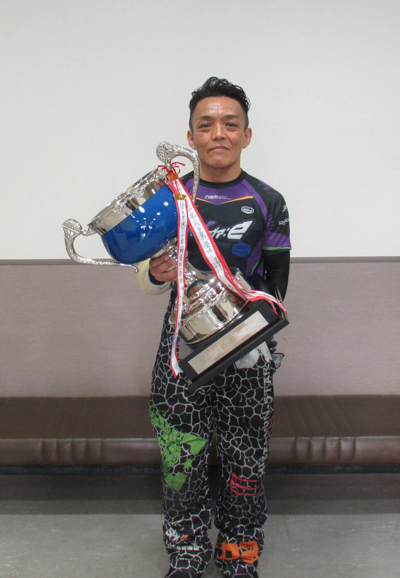 優勝トロフィーを手にほほ笑む黒崎竜也