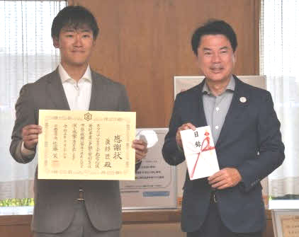 宇都宮市への寄付として佐藤栄一宇都宮市長（右）に目録を渡した真杉匠（外部提供）