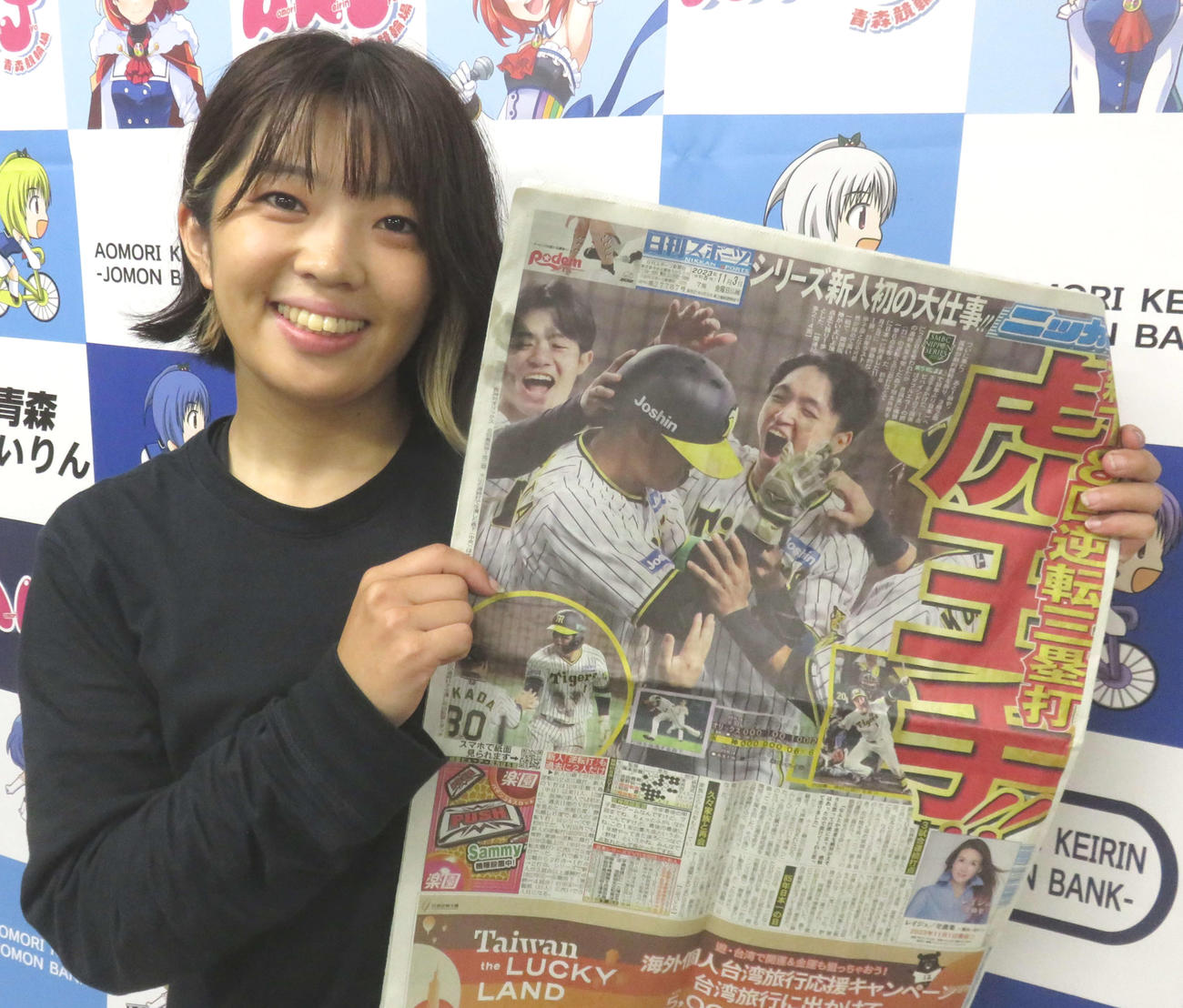 松井優佳は阪神の日本一王手を報じる3日付の日刊スポーツを手に笑顔（撮影・野島成浩）