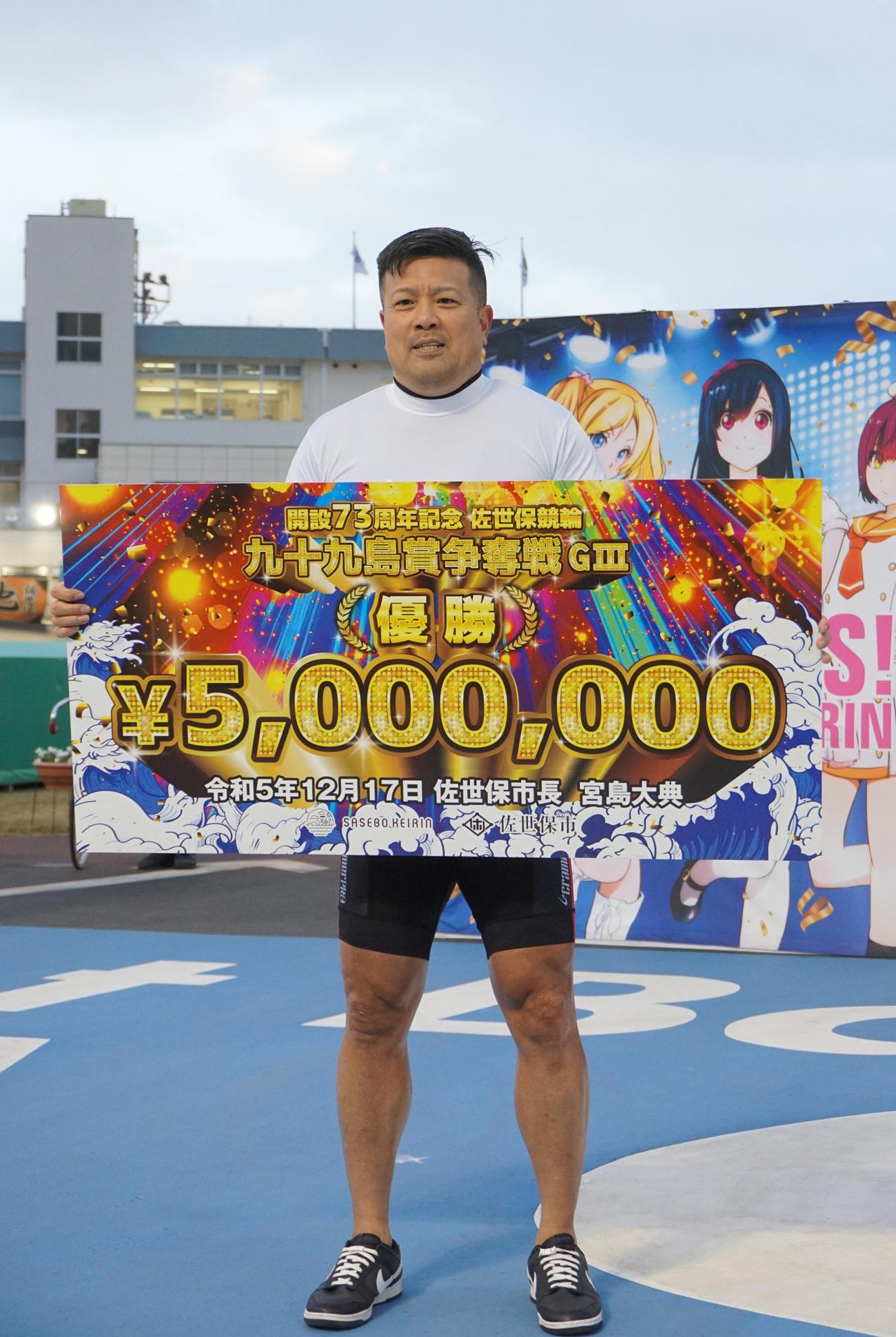 優勝した荒井崇博は賞金ボードを手に笑顔
