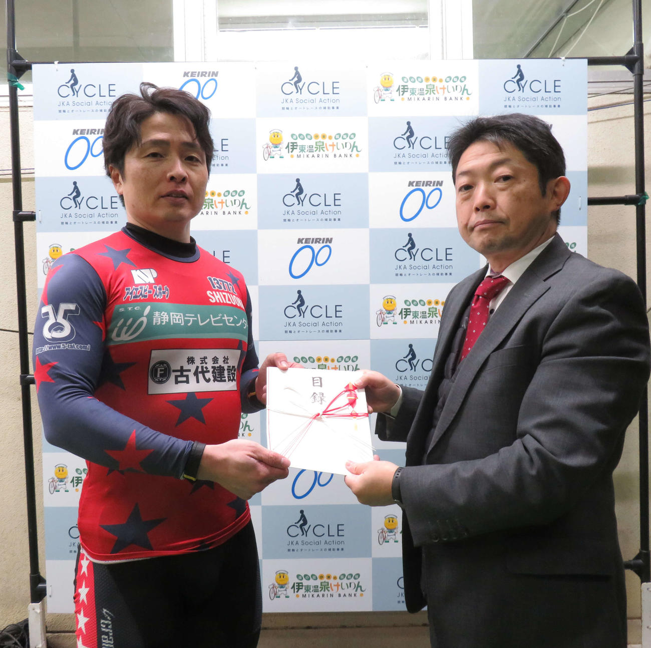 伊東市観光経済部公営競技事務所・福西淳所長に寄付の目録を手渡す岡村潤（撮影・栗田文人）