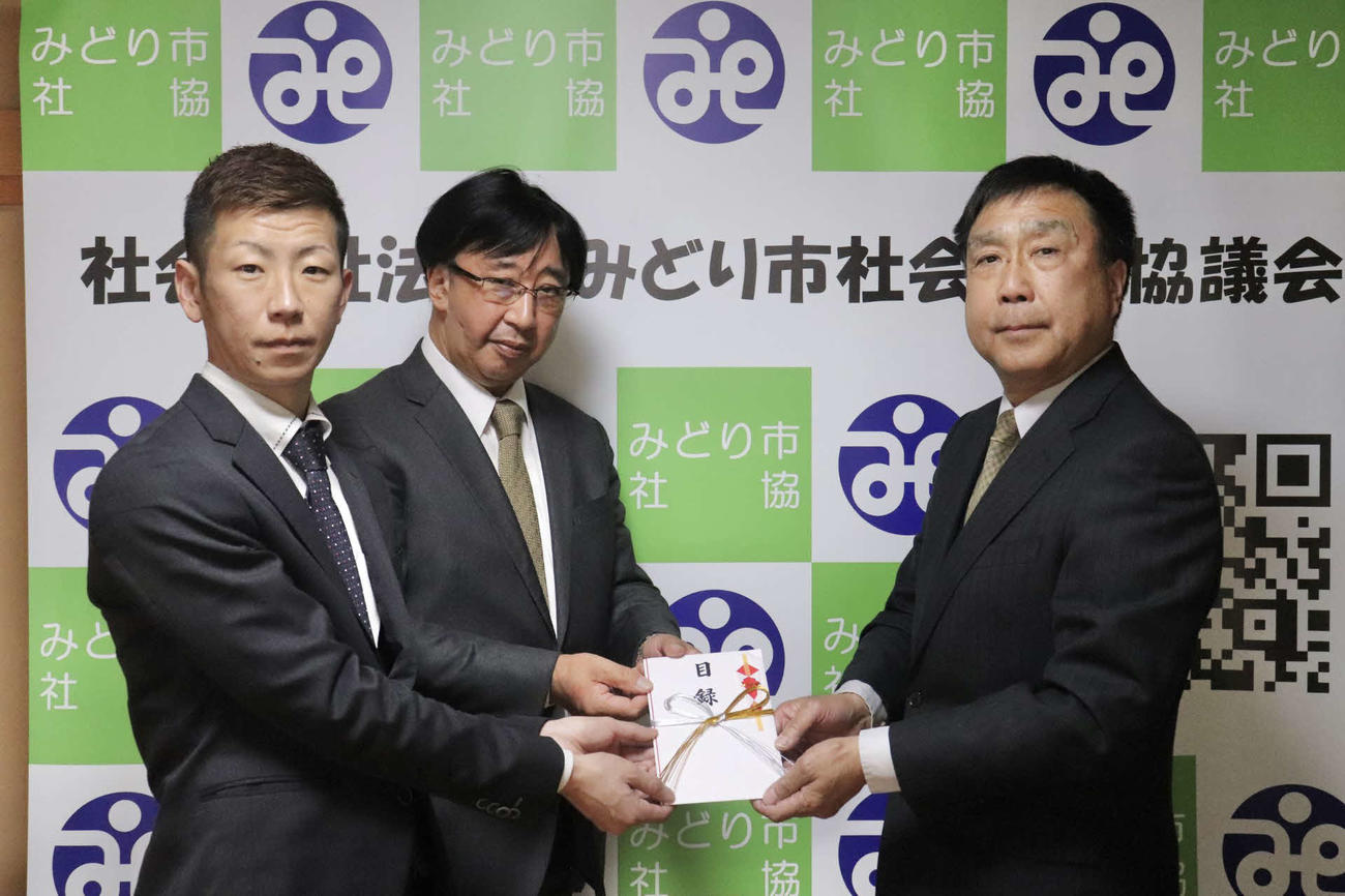 日本モーターボート選手会群馬支部理事長津久井拓也（左）、株式会社ボートネットワーク代表取締役社長山口明（中央）から、社会福祉法人みどり市社会福祉協議会古田島透常務理事・事務局長（右）へ目録が贈呈された