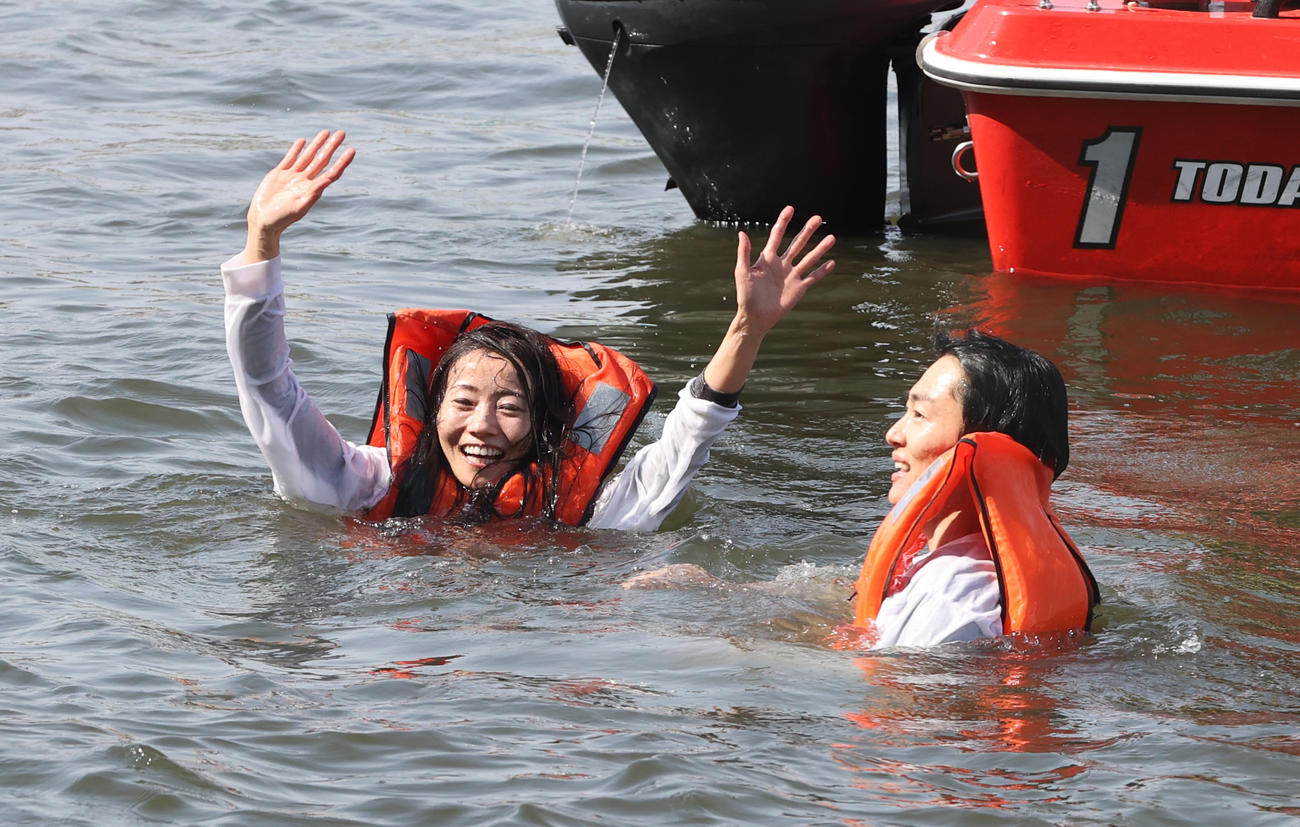 水神祭で水面に投げ込まれた浜田亜理沙はファンに手を振る、右は夫の中田竜太（撮影・柴田隆二）