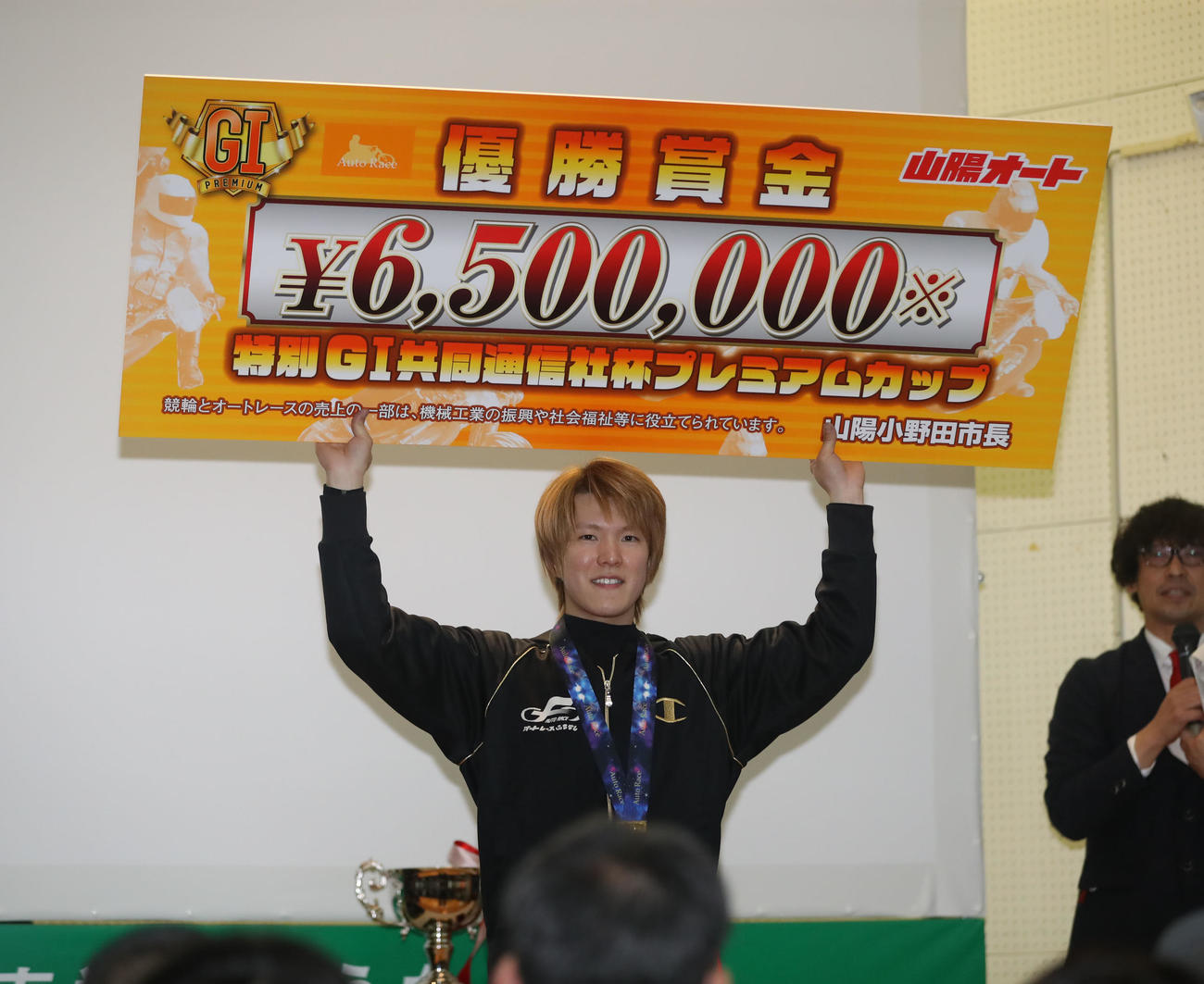 賞金ボードを掲げる鈴木圭一郎（撮影・冨田成美）