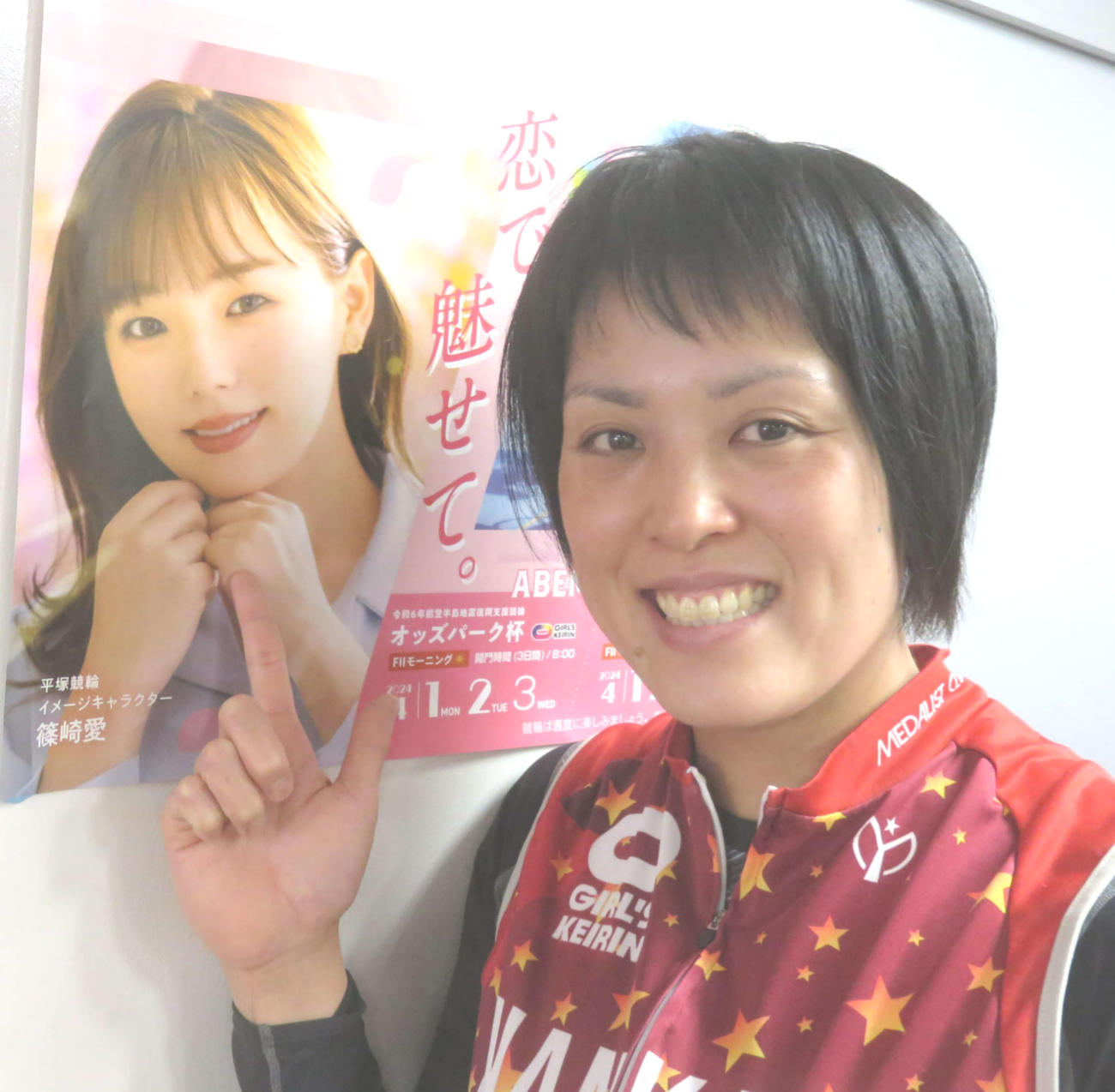 篠崎新純は24年度平塚競輪イメージキャラクター篠崎愛のポスターを指さし笑顔
