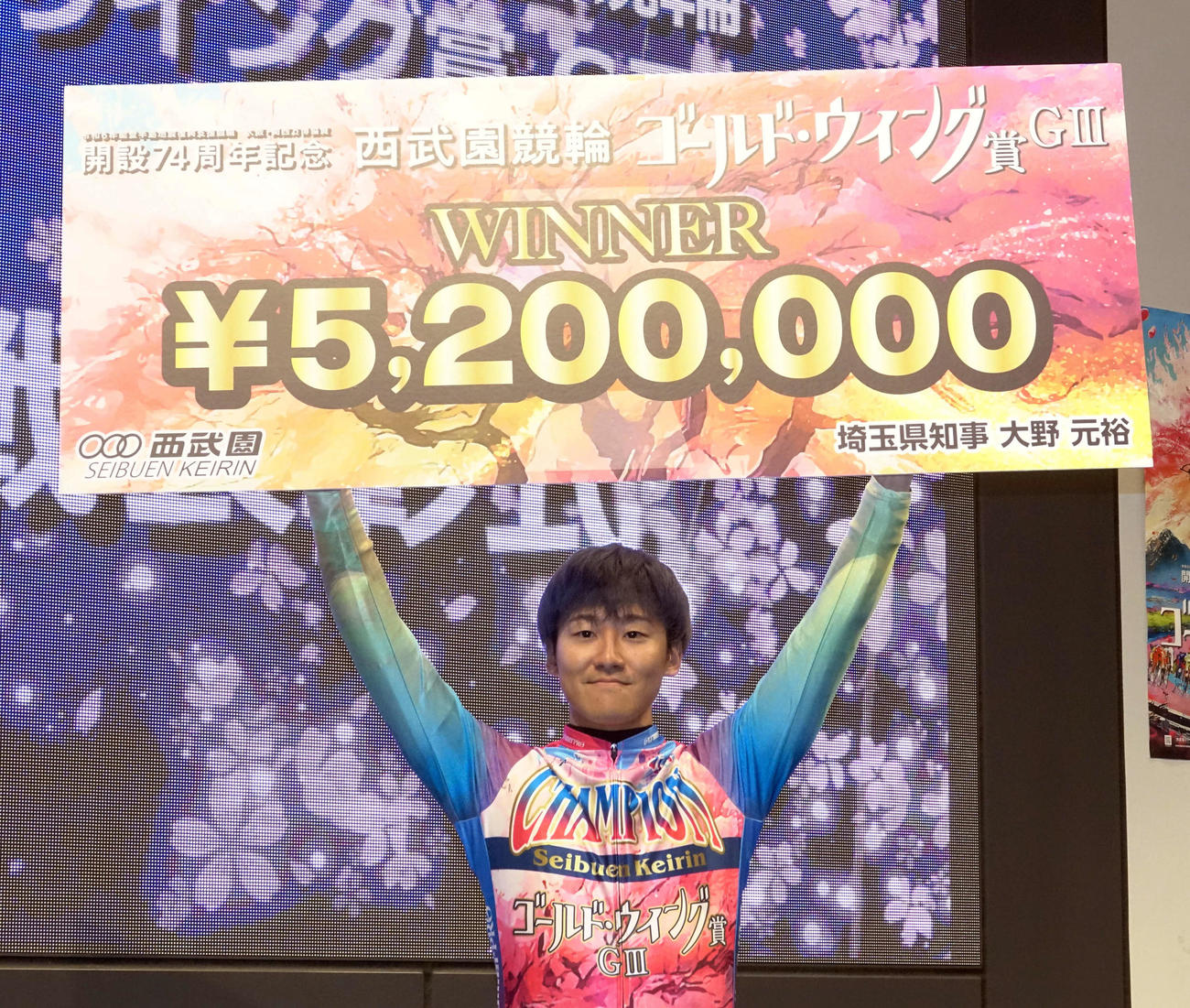 優勝した真杉匠は笑顔で賞金ボードを掲げる