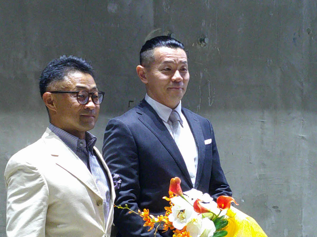 サプライズで登場した斎藤登志信（左）から花束をもらう稲村成浩さん