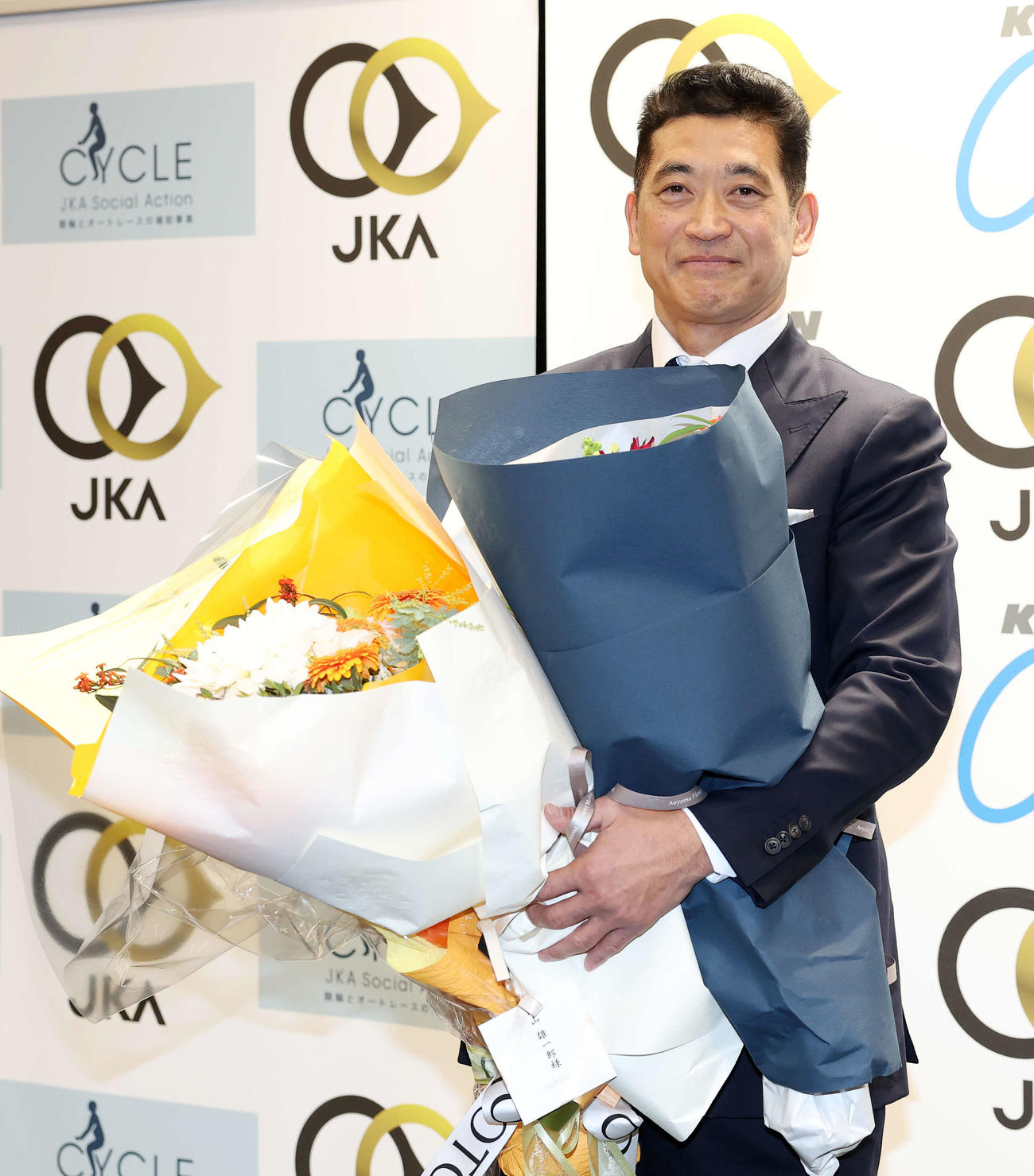 花束を手に写真に納まる神山（撮影・鈴木正人）