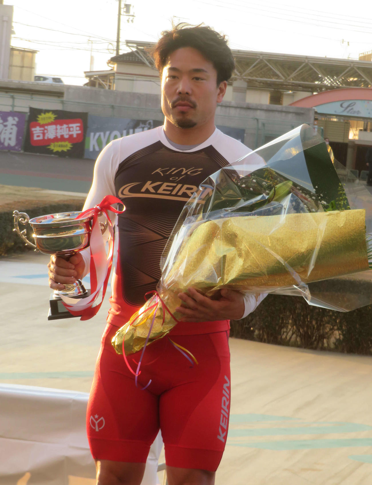 表彰式で優勝カップと花束を手にする古性優作