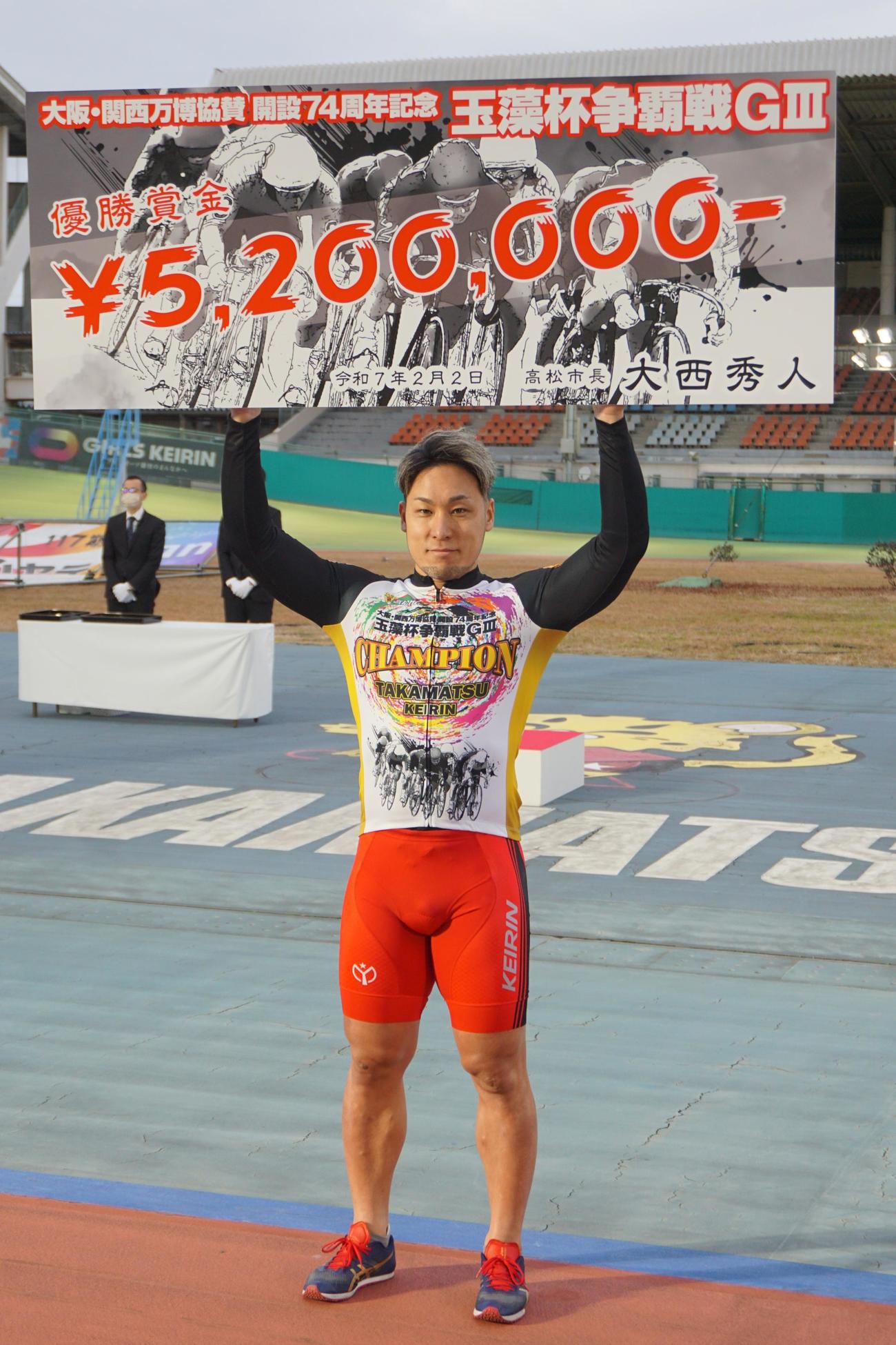 優勝した郡司浩平が賞金ボードを高らかに掲げた