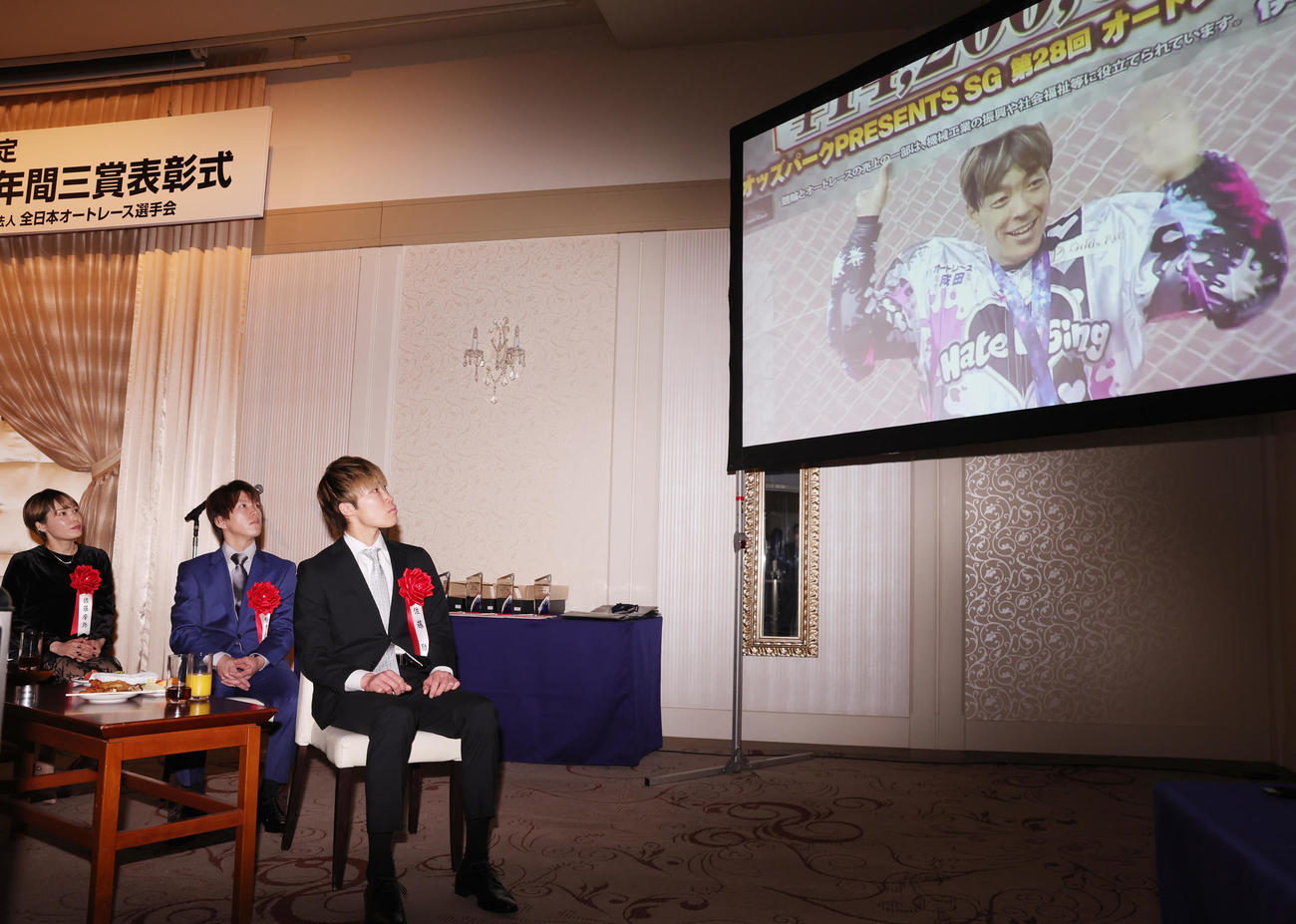 殊勲賞を受賞した青山周平のVTRを見つめる、左から佐藤摩弥、鈴木圭一郎、佐藤励（撮影・野上伸悟）