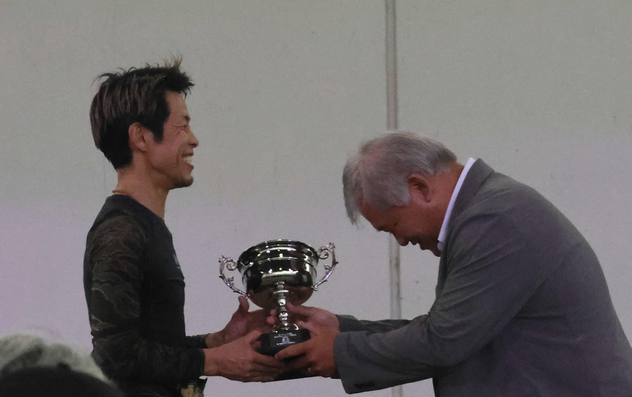 優勝した杉山正樹もびっくり！　本社でボート担当記者の経験が豊富な津波謙次メディア事業部公営戦略部長（写真右）から優勝カップが手渡された