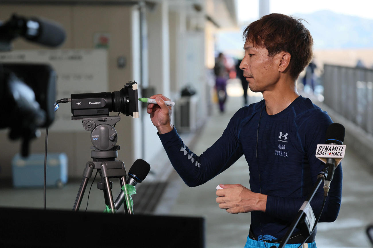 徳山3日目　10Rを制し中継カメラのレンズにサインする吉田拡郎（撮影・宮崎幸一)