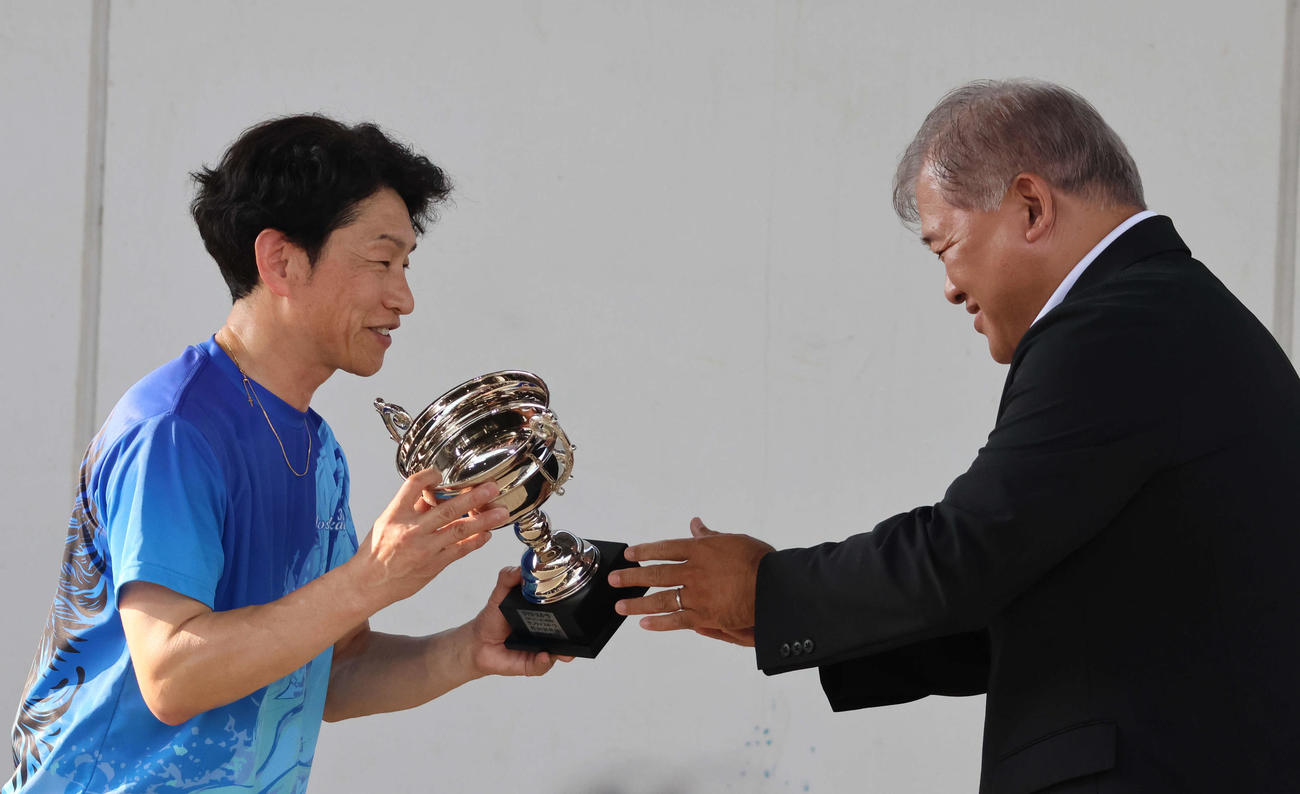 優勝した吉川元浩から「お久しぶりです」と声をかけられた本社の津波謙次メディア事業部公営戦略部長（写真右）から優勝カップが手渡され、笑顔を浮かべた（撮影・北條直治）
