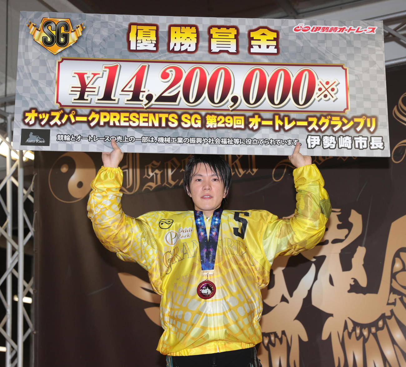 優勝した鈴木圭一郎は賞金ボードを掲げる（撮影・柴田隆二）