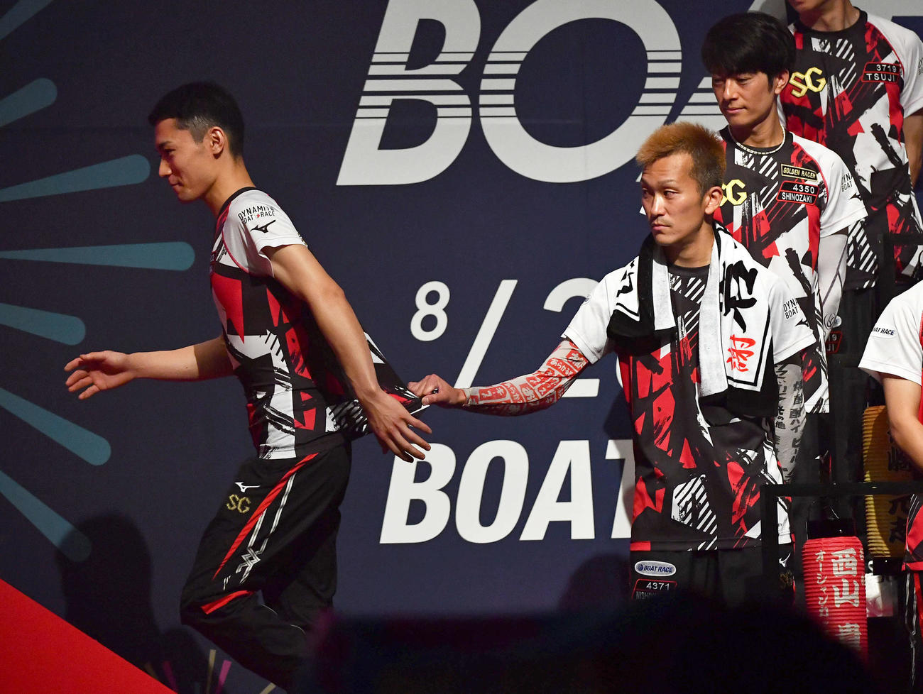 SGボートレースメモリアル1日目　開会式で選手代表あいさつに向かう4932新開航（左）の服をひっぱる4371西山貴浩（撮影・岩下翔太）