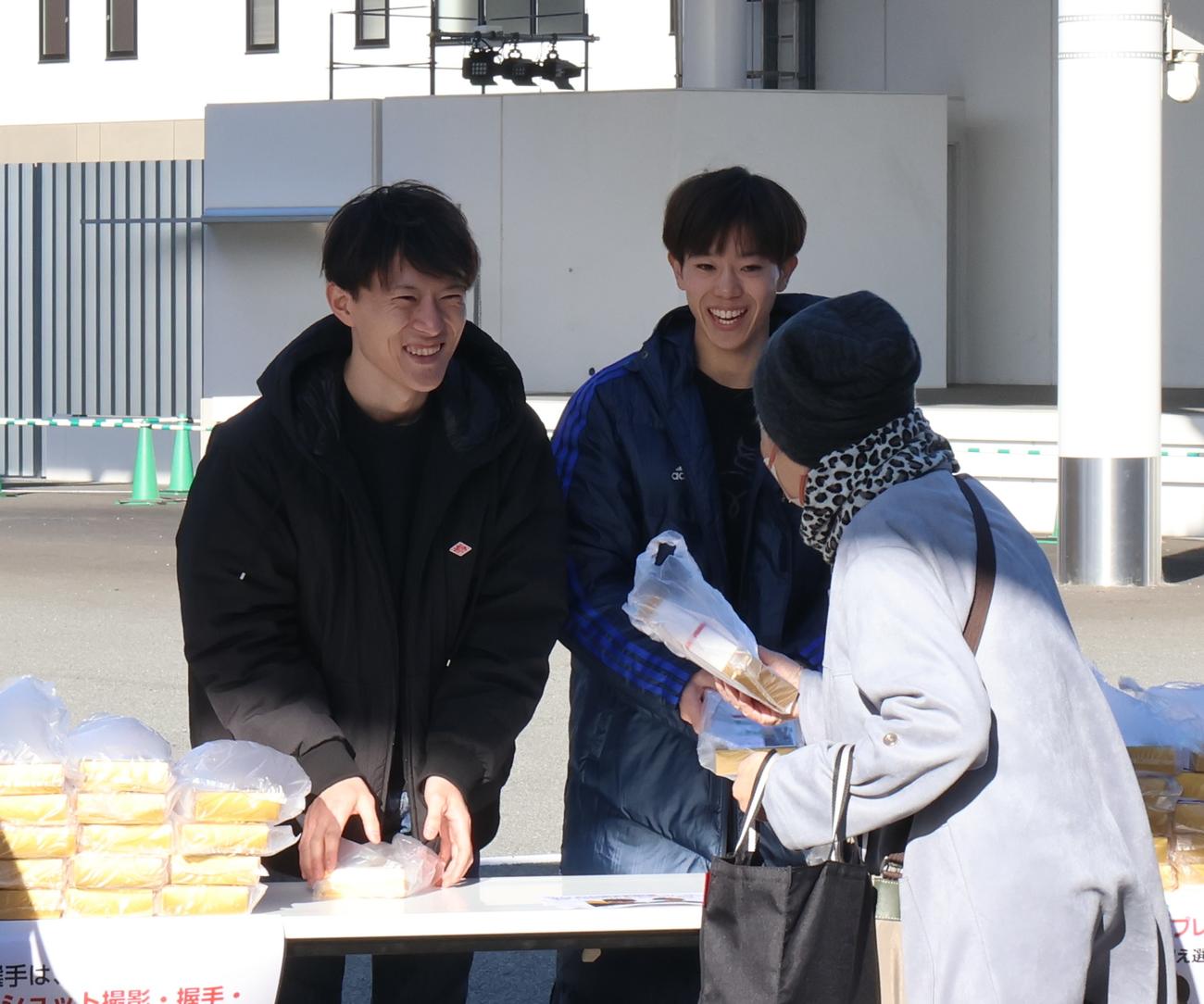 先着プレゼントを手渡す藤本元輝（左）と山下拓巳