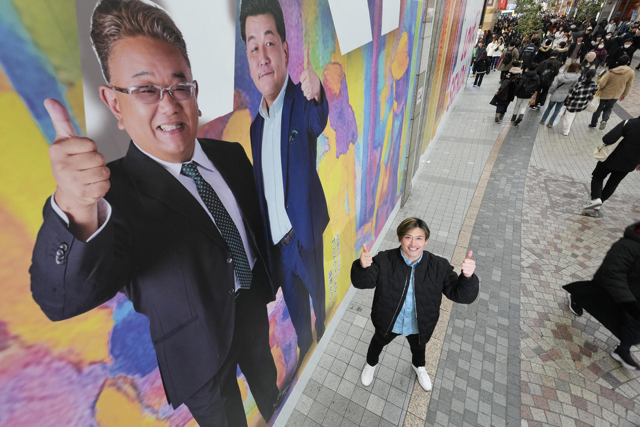 仙台駅前のクリスロード商店街にあるアート看板の前で、初のグランプリへ向けてガッツポーズで気合を示す阿部拓真（2025年12月撮影）