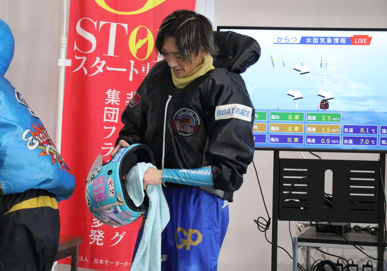うつむいてヘルメットを手入れする峰竜太