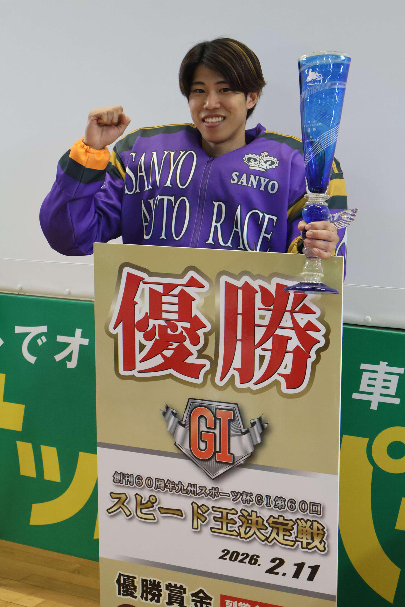 ガラス製のトロフィーを手に笑顔の長田稚也