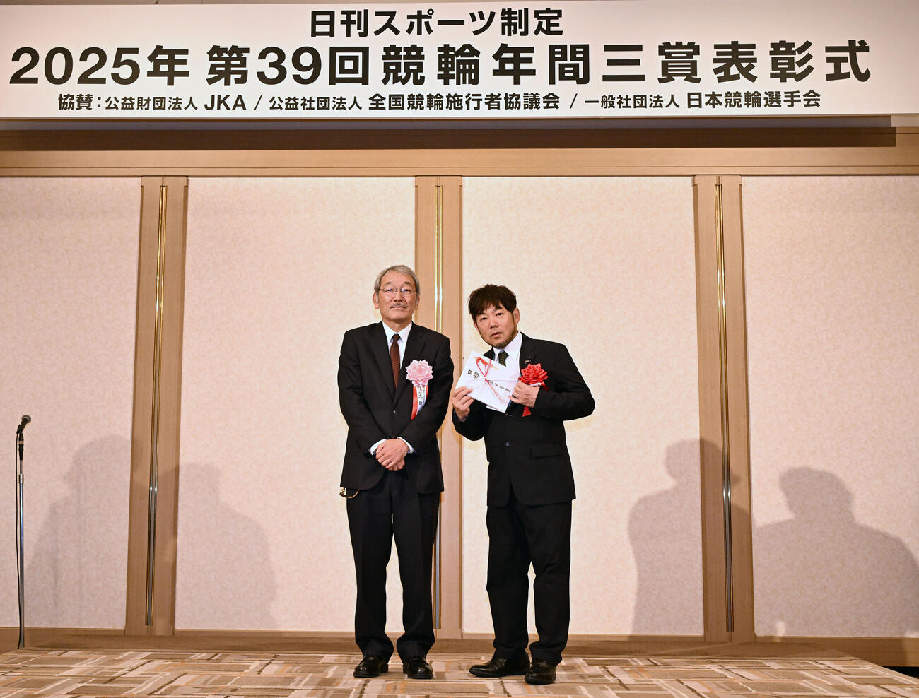 日刊スポーツ制定2025年第39回競輪年間三賞表彰式　日刊スポーツの高田社長（左）と記念写真に納まるガールズ特別賞を受賞した佐藤の代理の日本競輪選手会の古原常務理事（撮影・千葉一成）