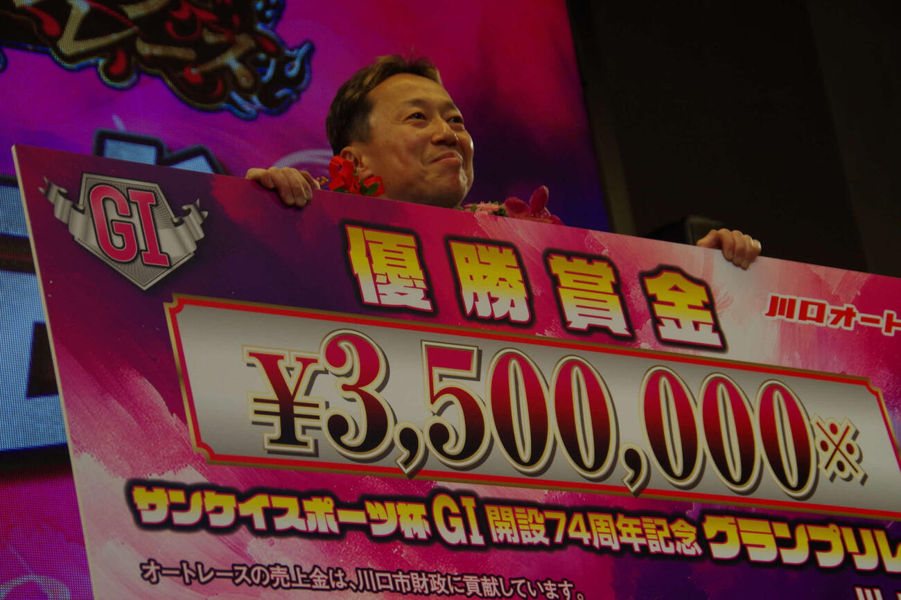 大会連覇の高橋義弘が優勝小切手パネルを手に笑顔