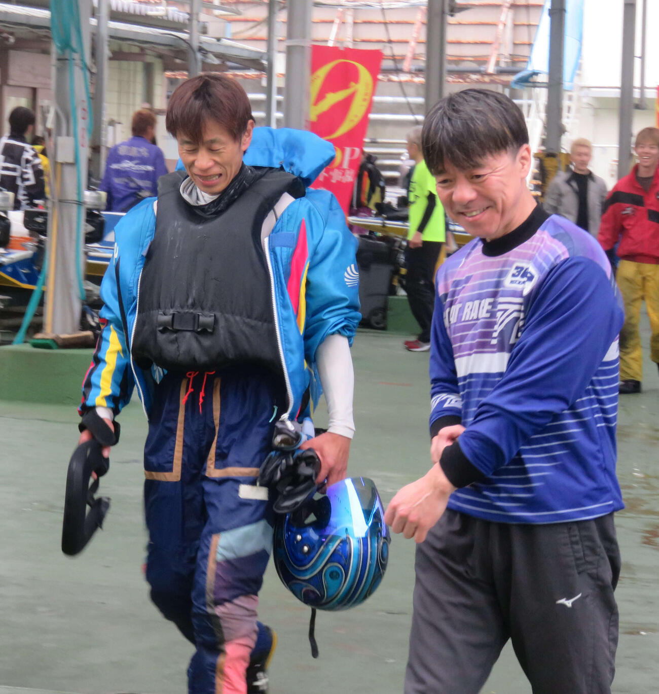 通算1500勝を達成した妹尾忠幸（左）は笑顔を交わし井上恵一に迎えられる