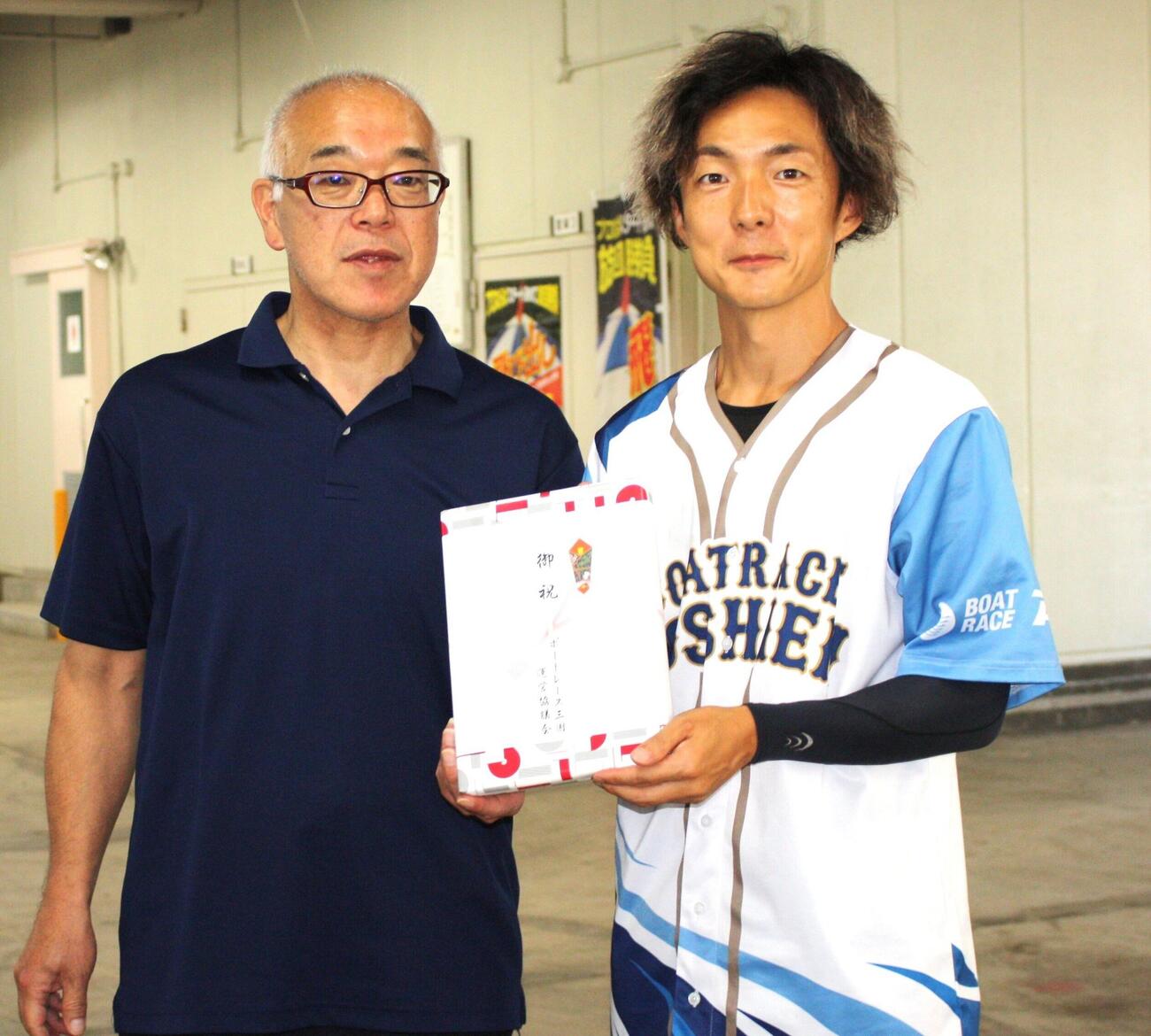 初日1Rで10連勝を達成した松田祐季（右）は事業局長からお祝いの商品を受け取る